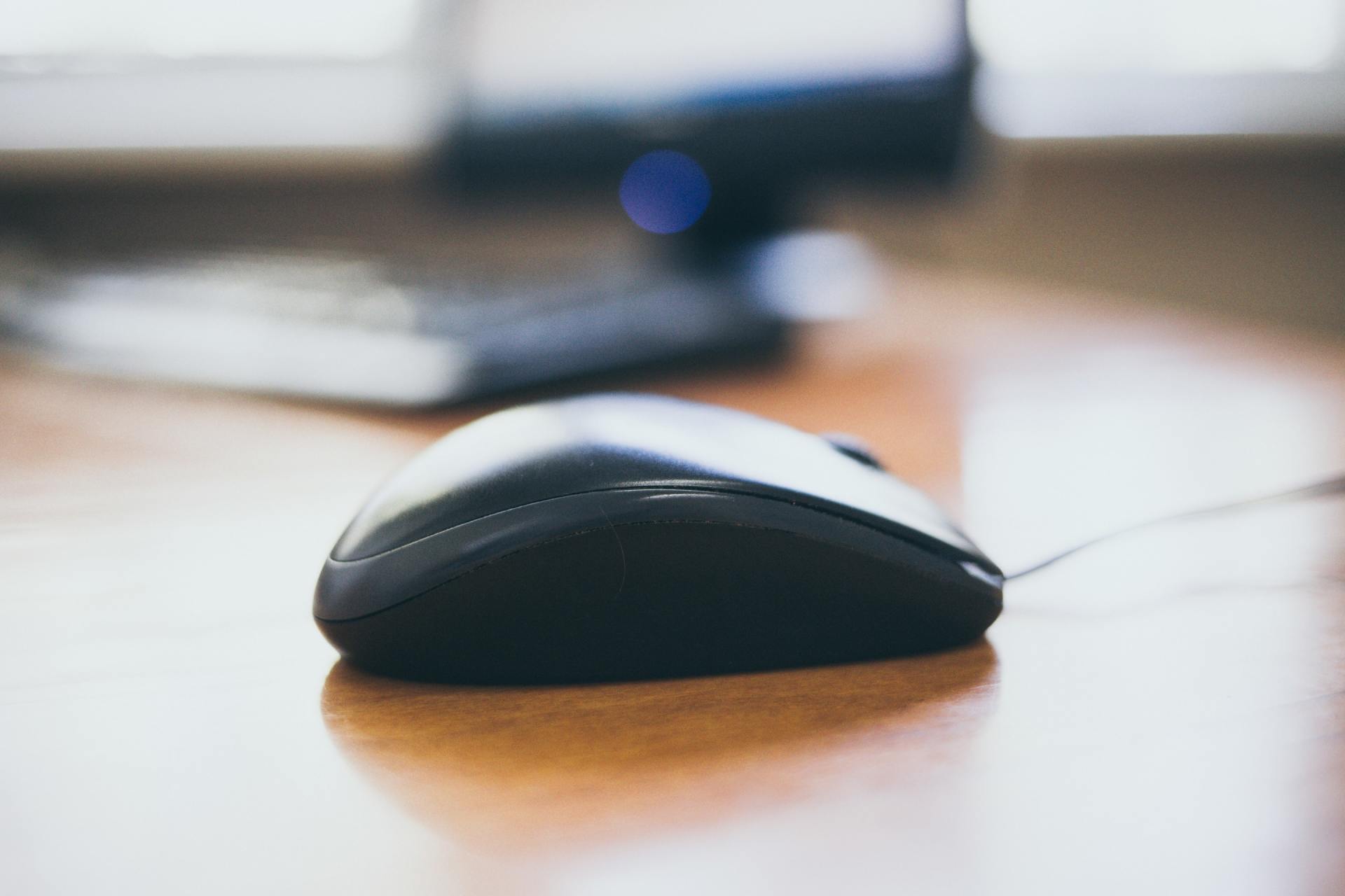 a computer mouse is sitting on a wooden desk in front of a computer monitor .