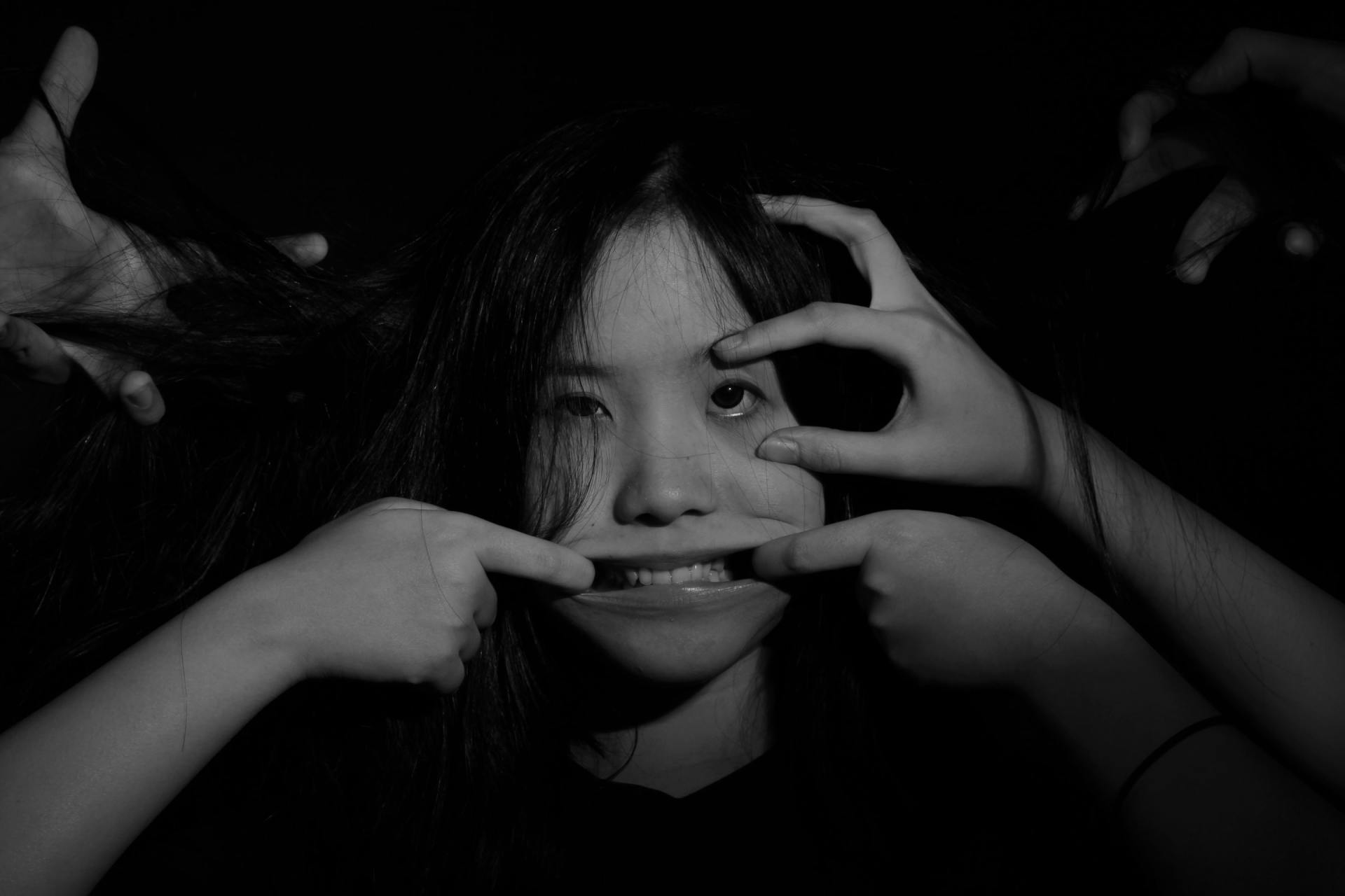 A black and white photo of a woman making a face with her hands.