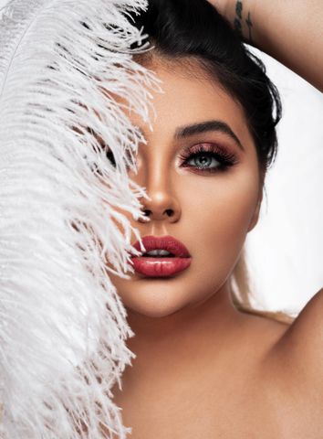 A woman is holding an ostrich feather in front of her face.
