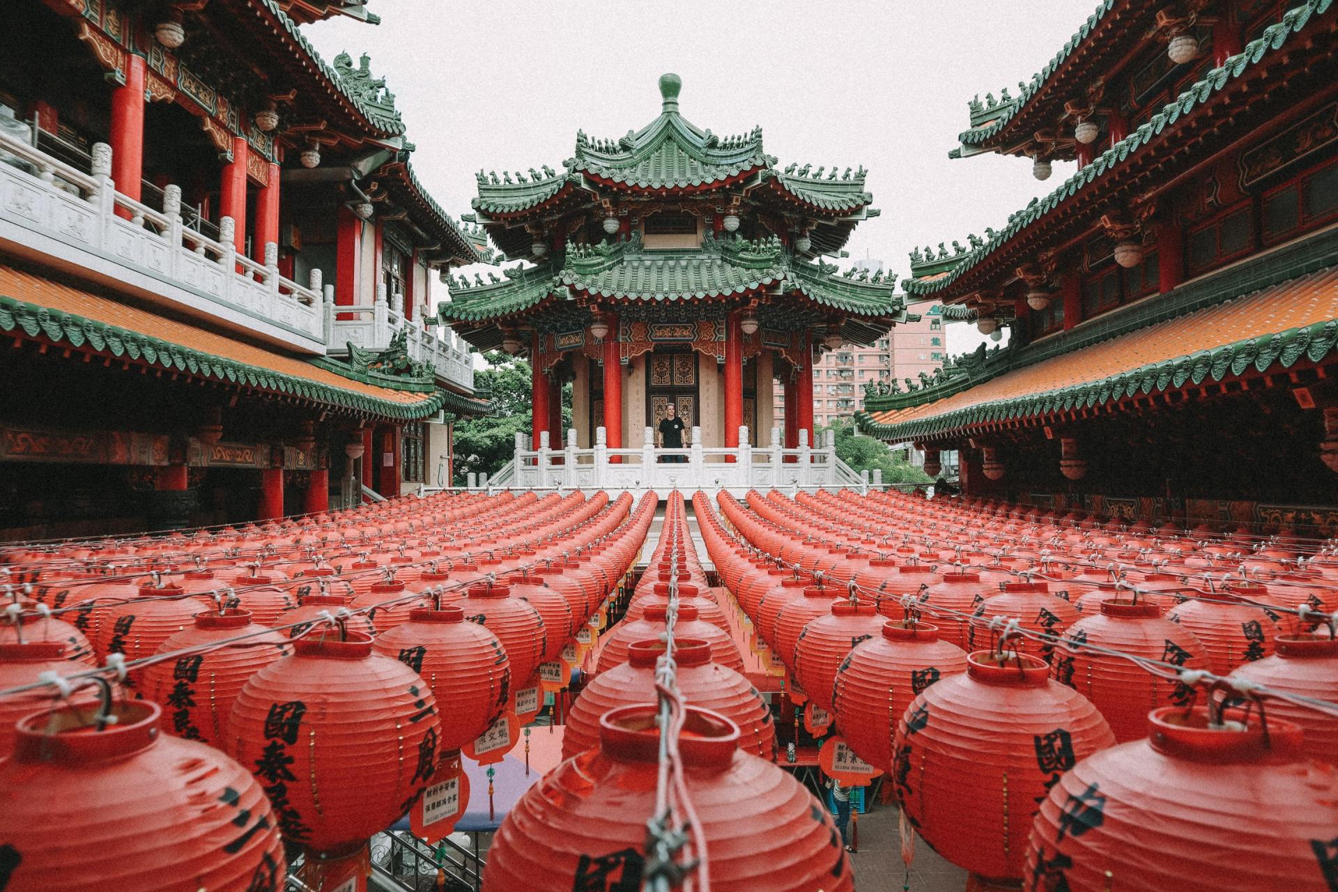 Eine Reihe roter Laternen steht vor einem chinesischen Gebäude.
