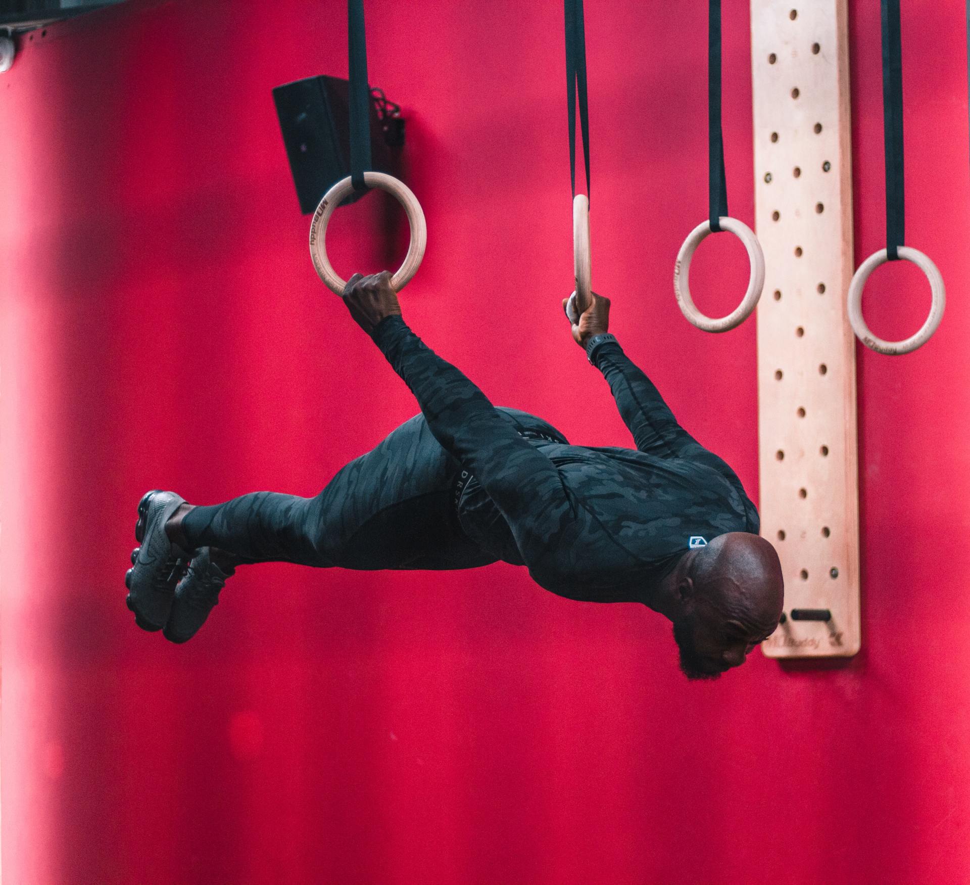 A man is doing a handstand on gymnastic rings