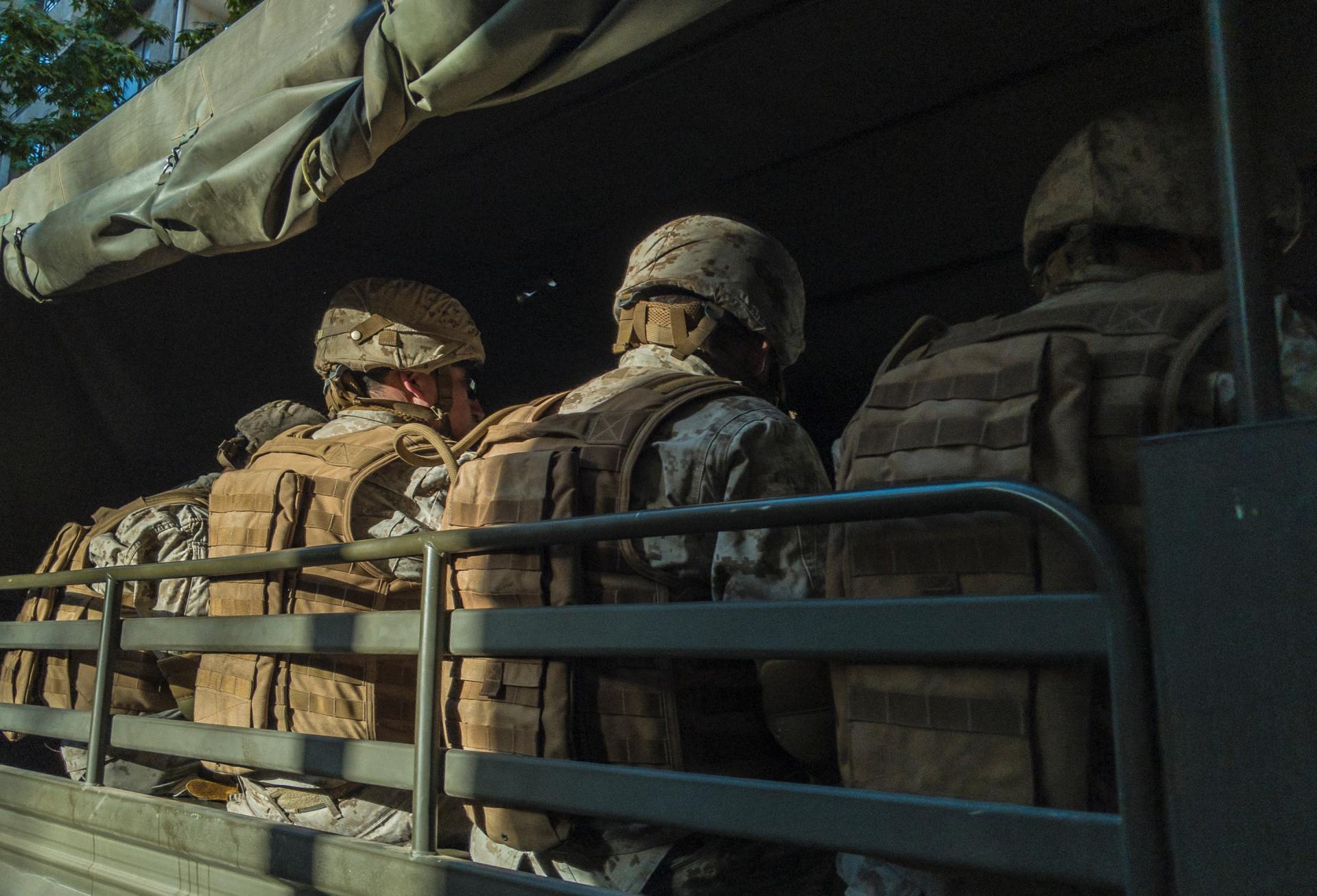 a group of soldiers are sitting in the back of a truck .