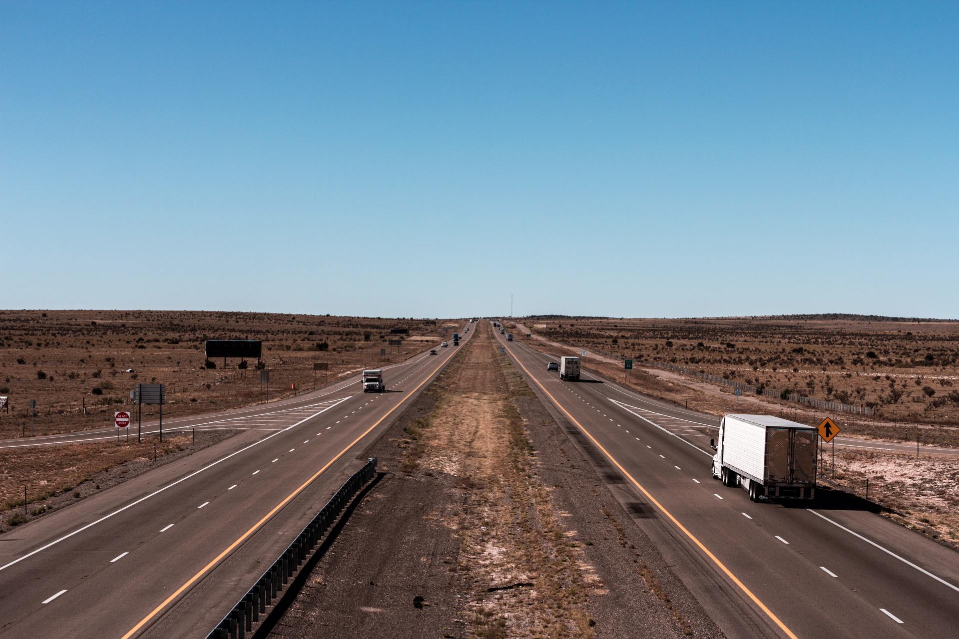 A truck is driving down a highway in the desert.