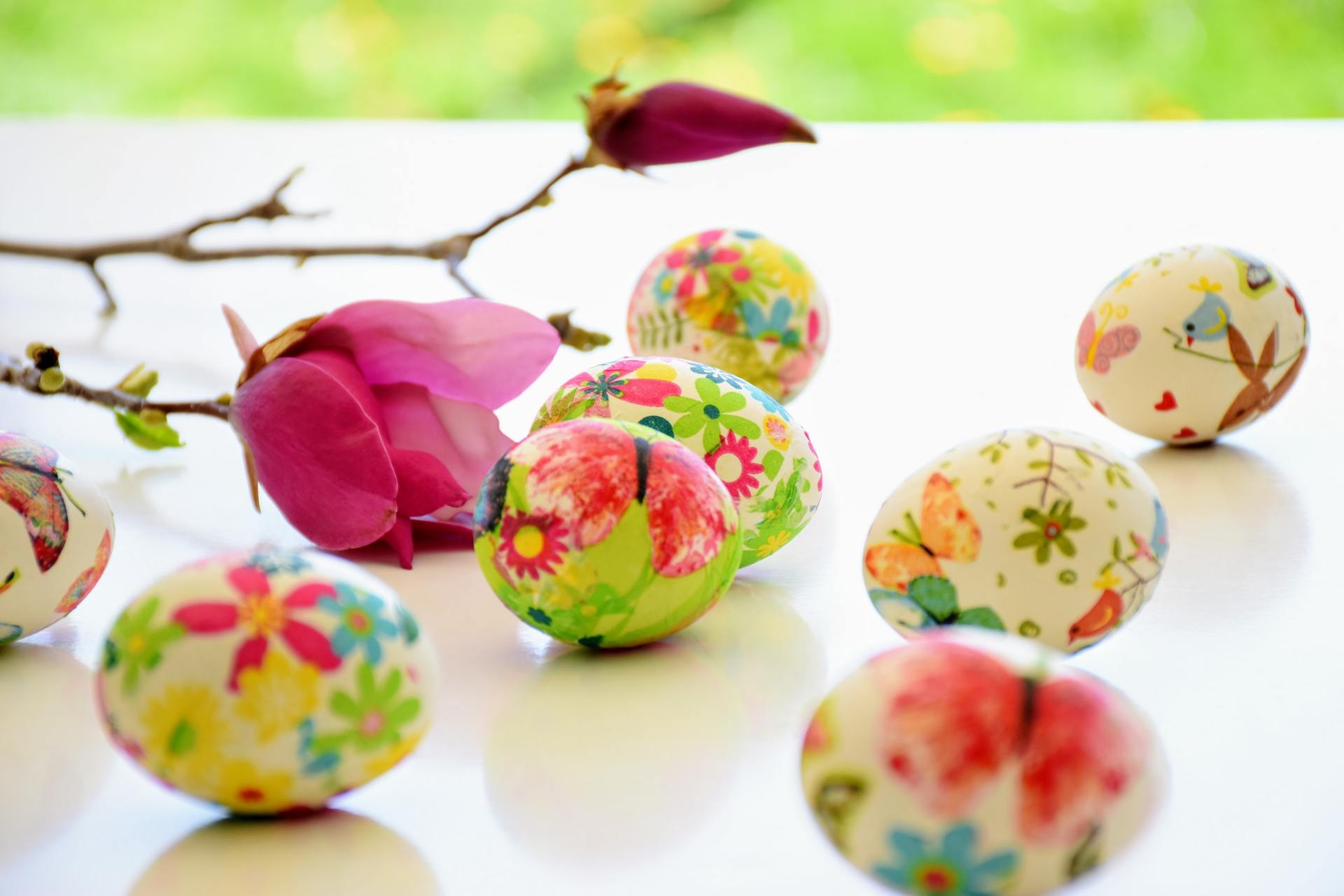 Un bouquet d'œufs de Pâques colorés avec des fleurs dessus sur une table.