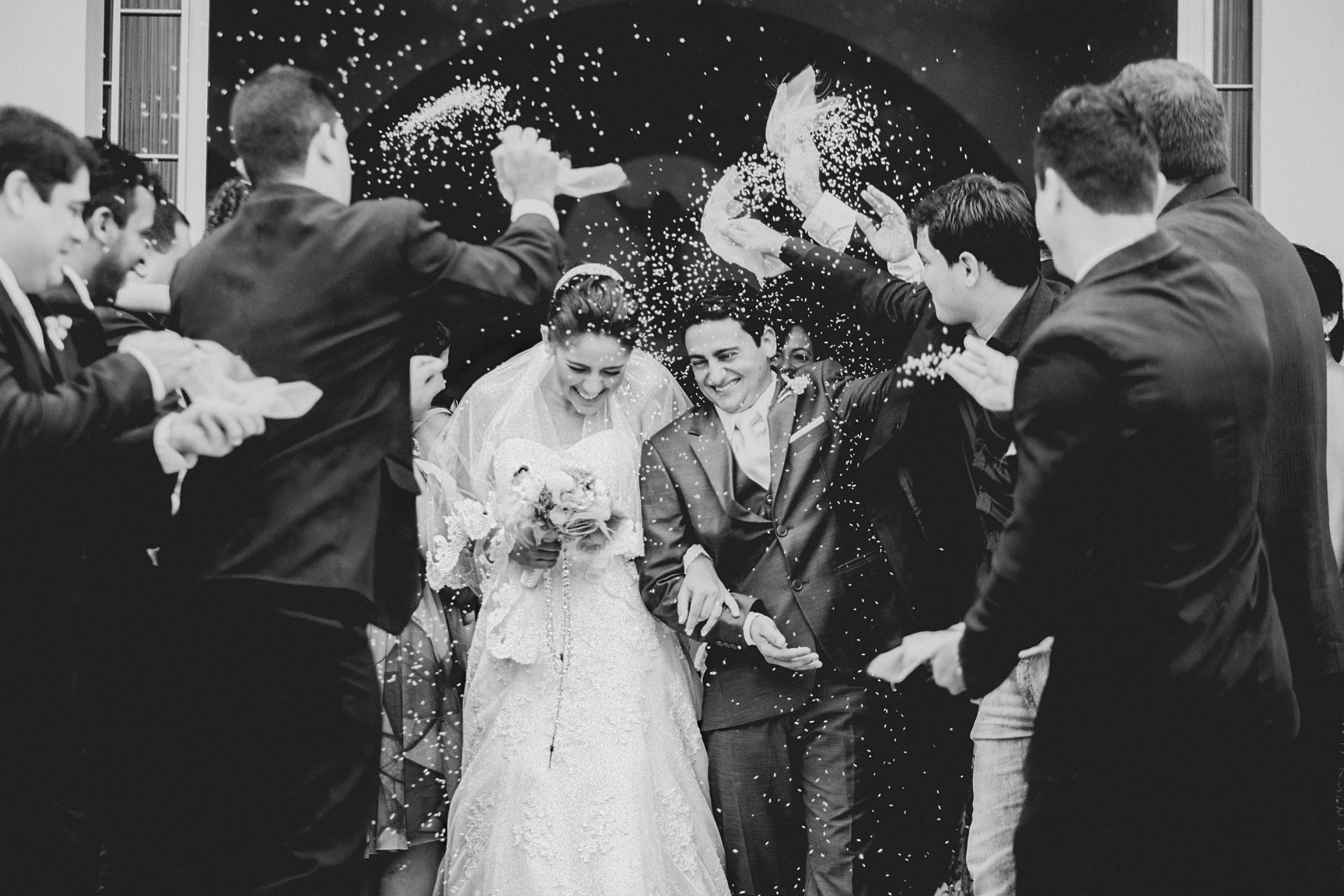 Newlyweds exiting a building, showered in confetti by cheering guests.