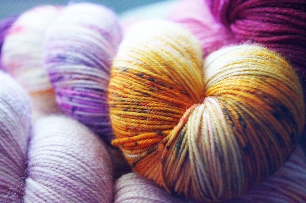 A bunch of balls of yarn of different colors are stacked on top of each other.