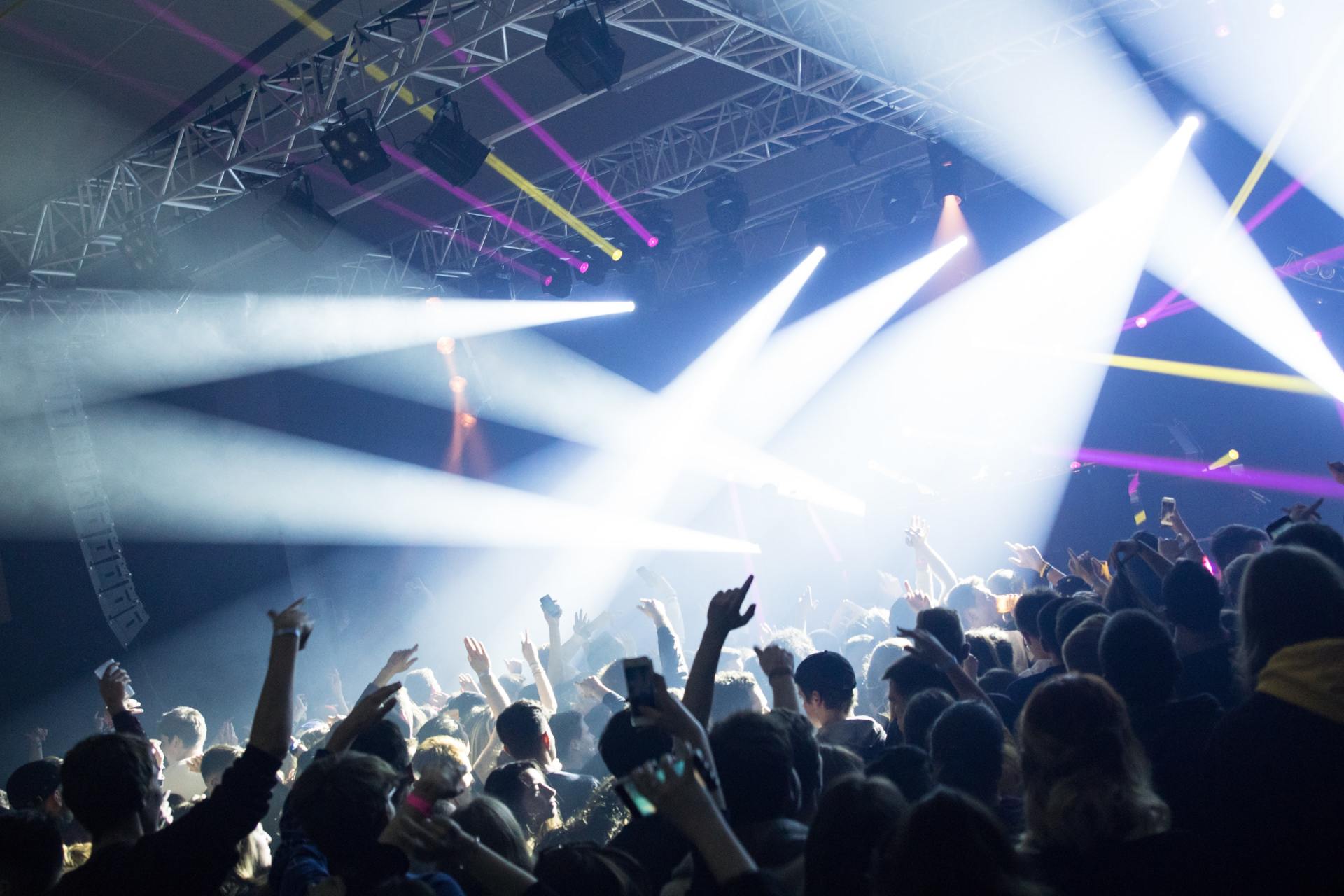A crowd of people at a concert with their hands in the air.