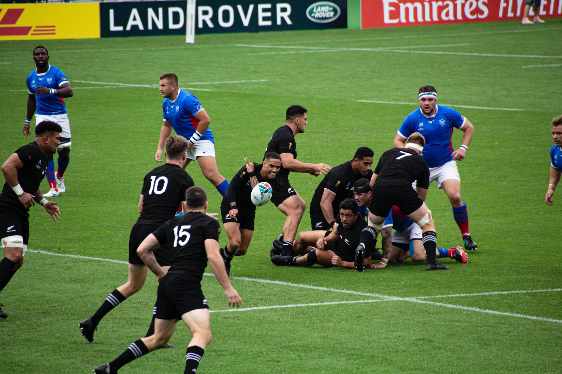 A group of rugby players are playing a game on a field sponsored by land rover.