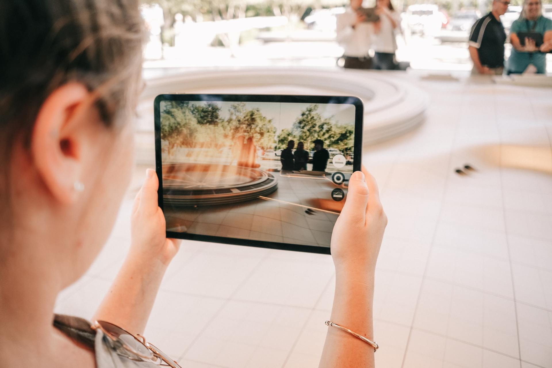 Person photographing a fountain scene on a tablet in a bright indoor mall