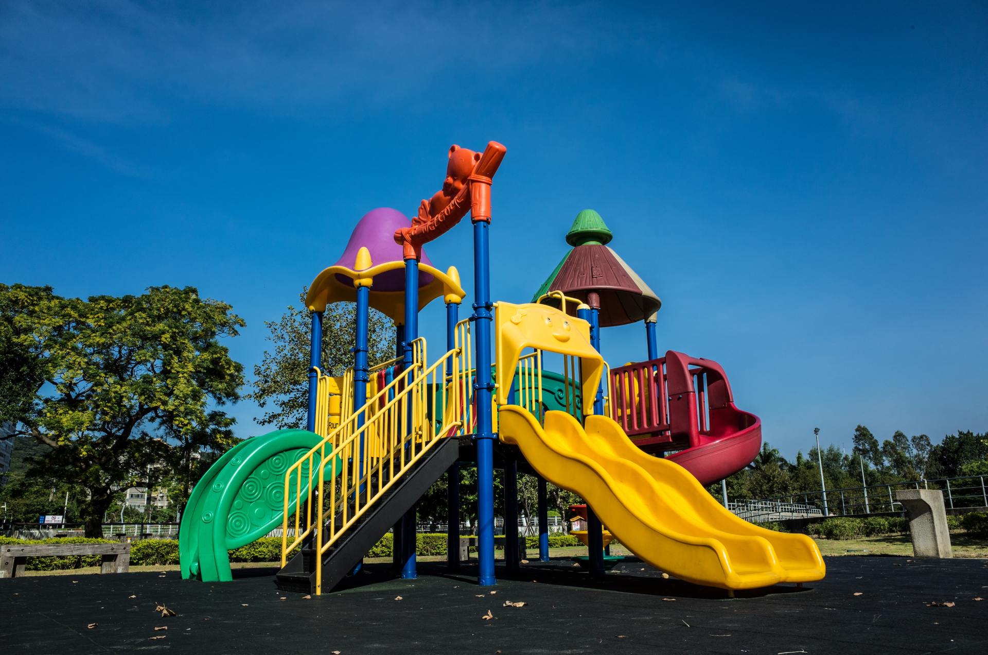 A colorful playground set in a park with trees in the background.