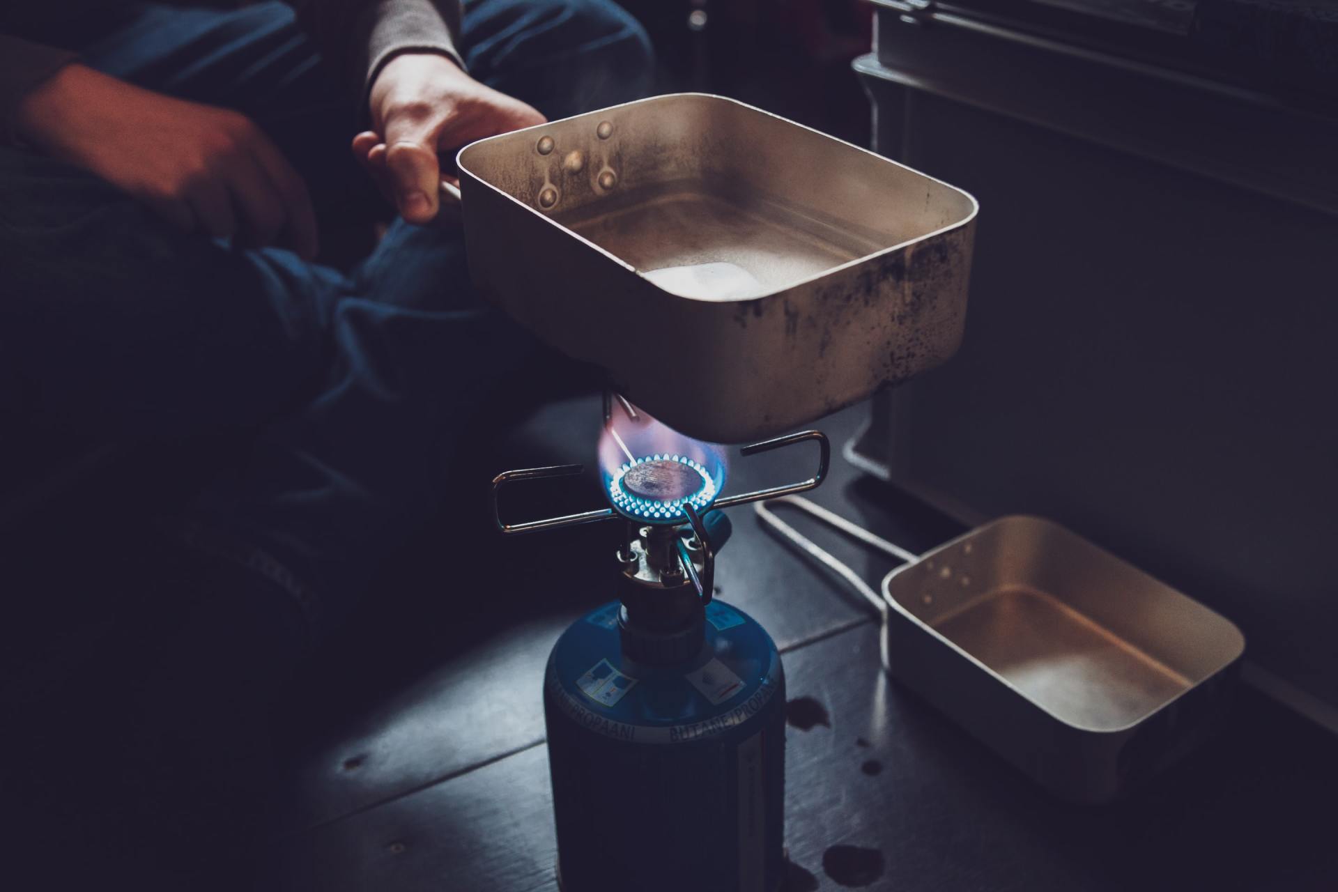 A person is cooking on a small gas stove