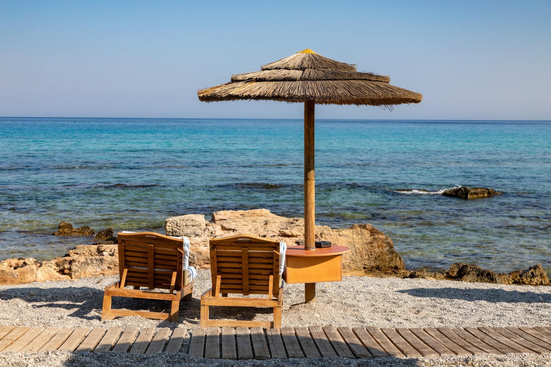Two chairs under an umbrella on the beach.