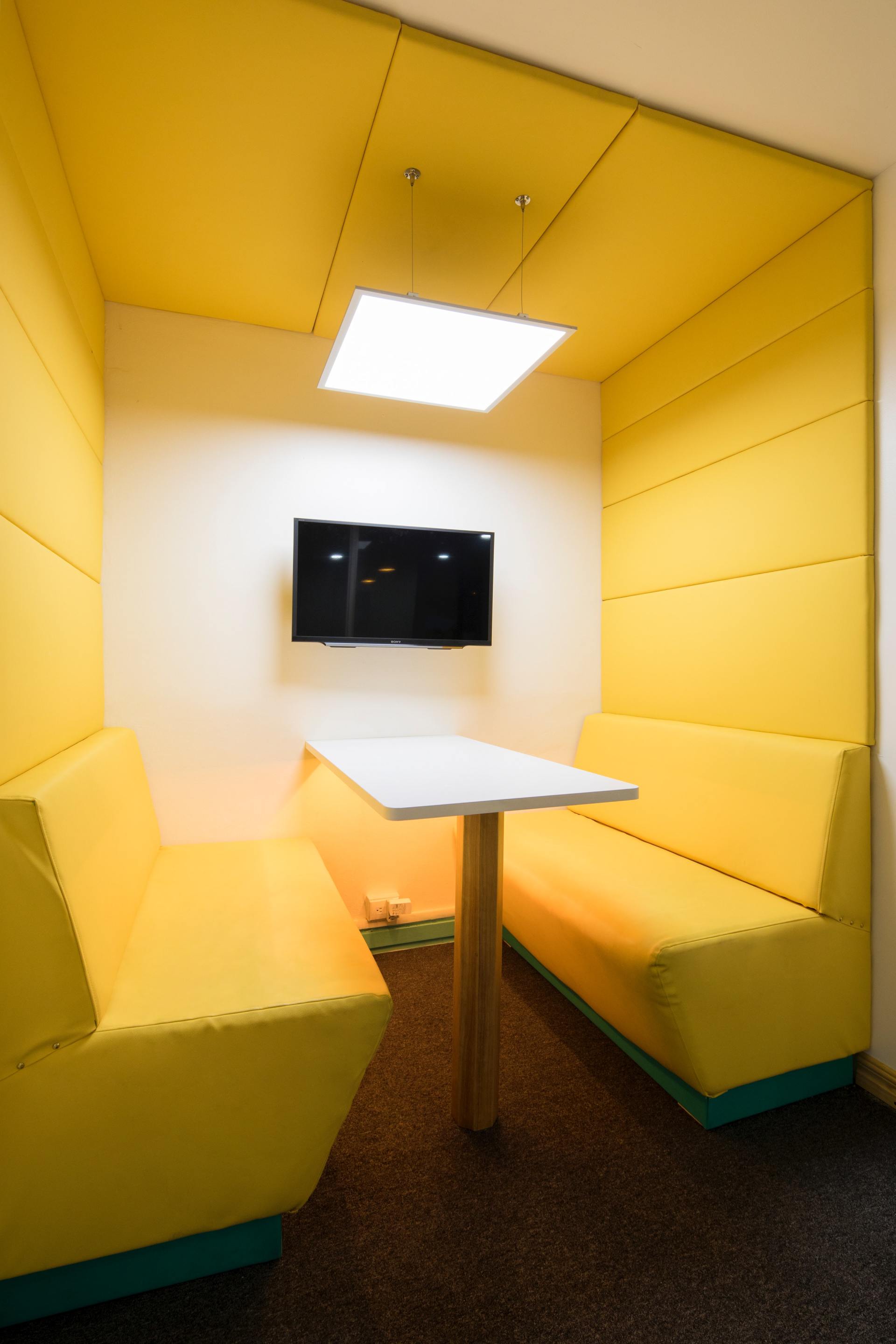 A small room with yellow benches and a table.