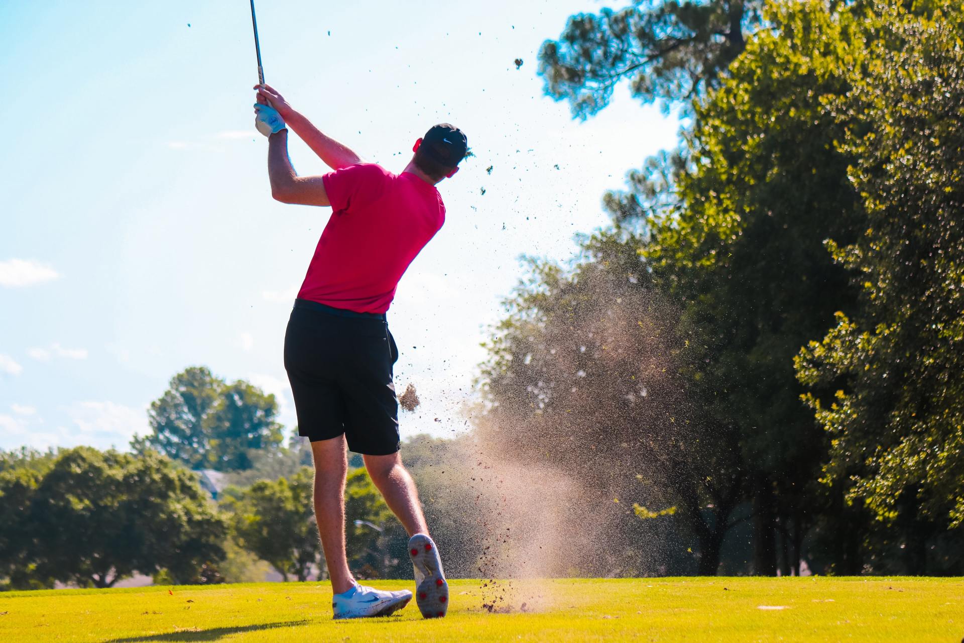 A man is swinging a golf club on a golf course.