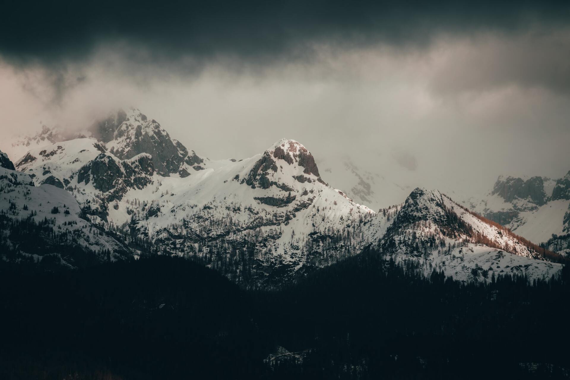 A snowy mountain range with a cloudy sky in the background.