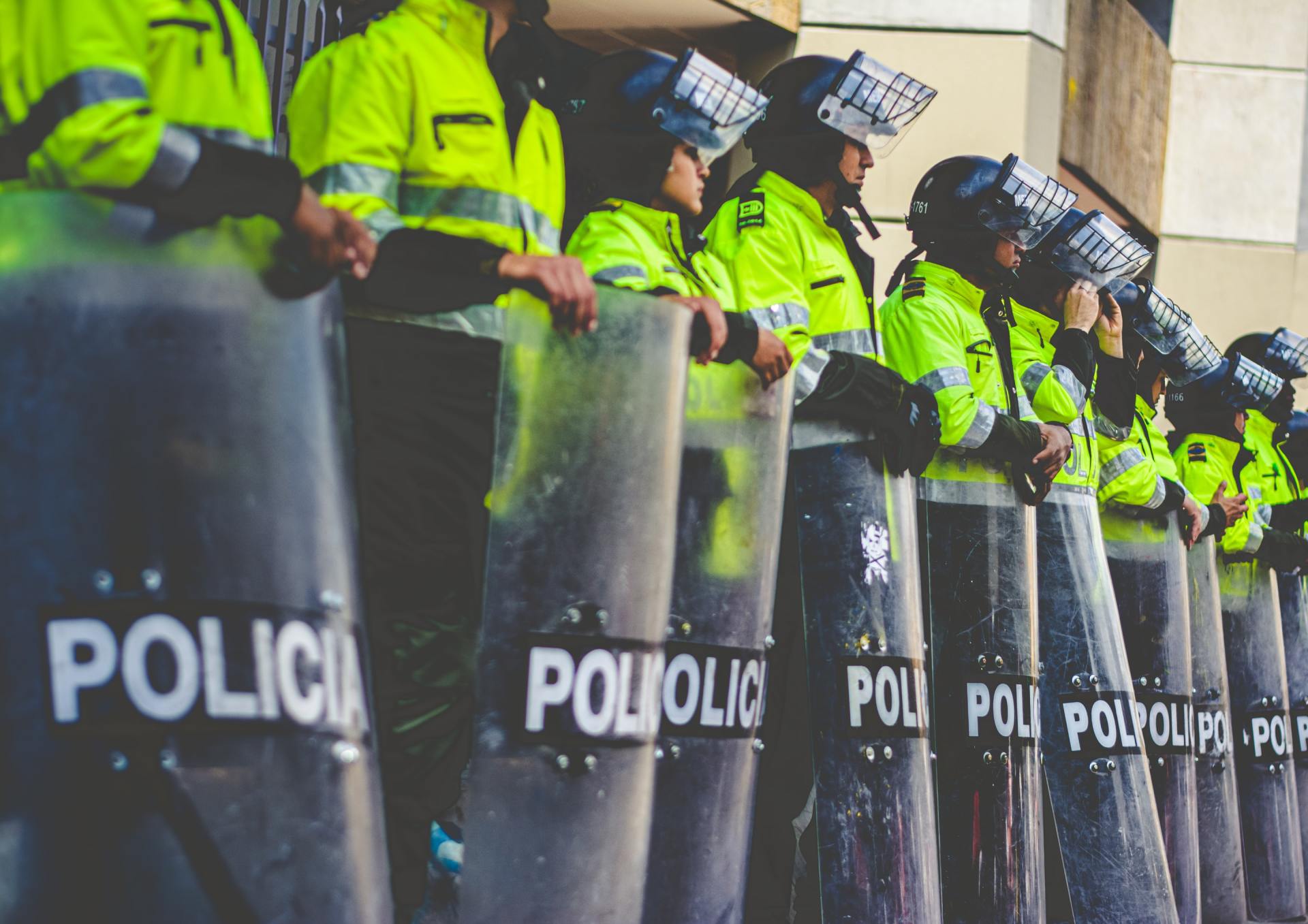 A row of police officers standing next to each other wearing riot gear.