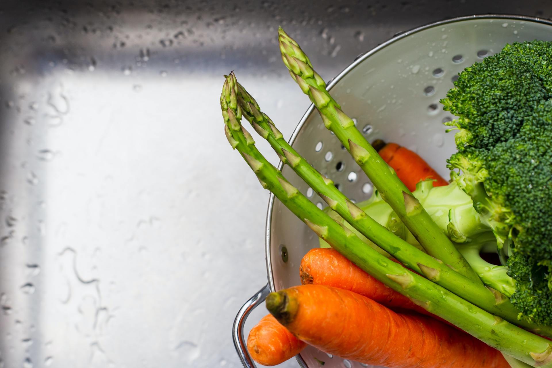 Le brocoli, les carottes et les asperges sont rincés dans un évier.