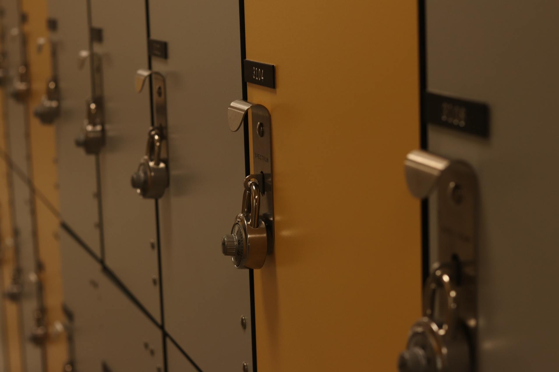 Een rij beige schoolkluisjes met metalen sloten en handgrepen