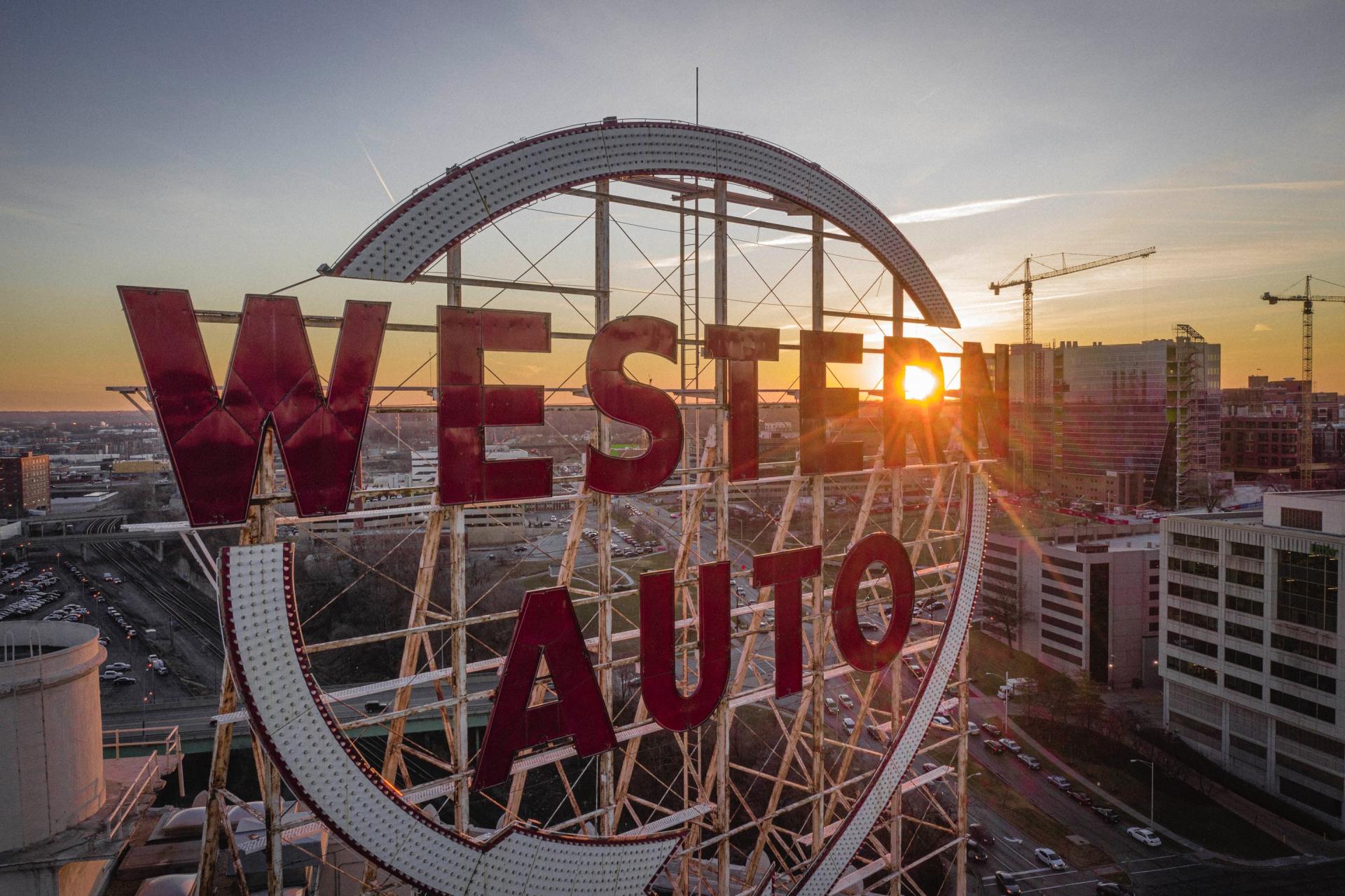 An aerial view of a western auto sign in a city at sunset.