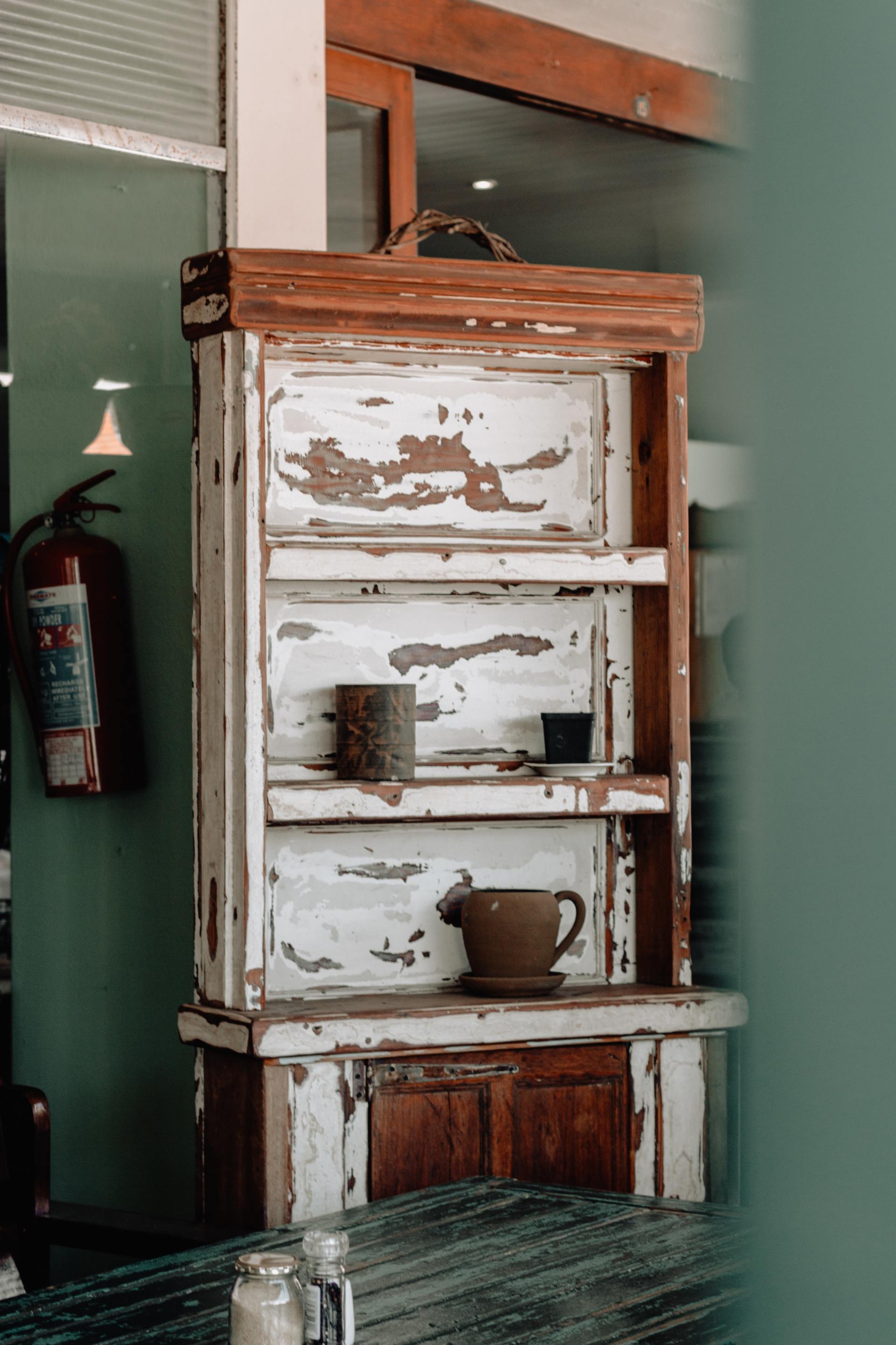 A wooden shelf with a cup on it is sitting on a table.