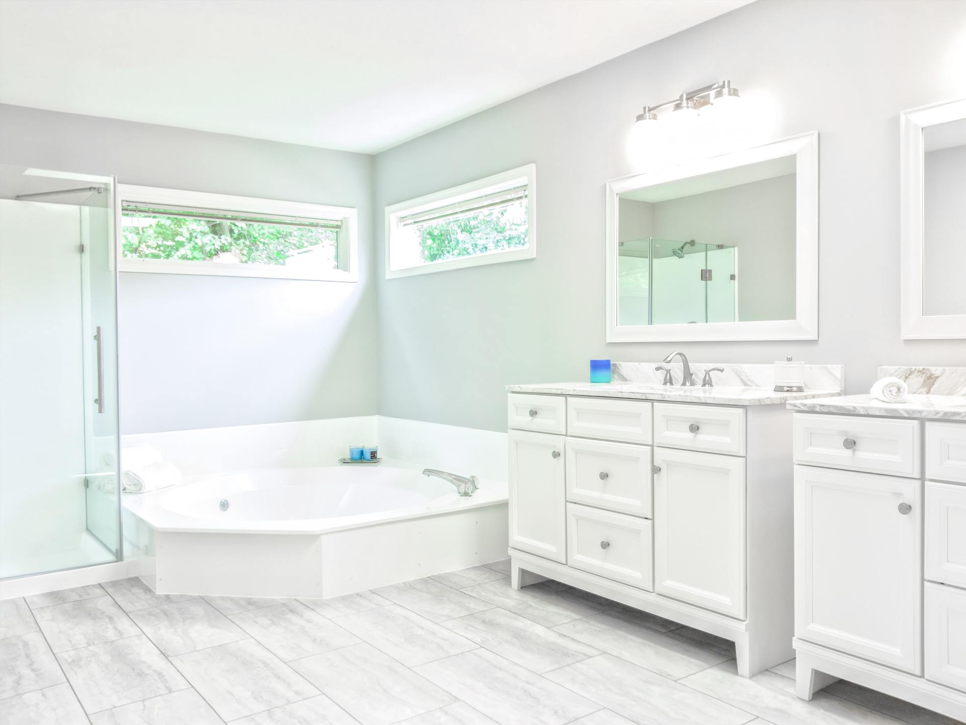 Modern bathroom with white cabinets, tub, shower, and light gray walls.
