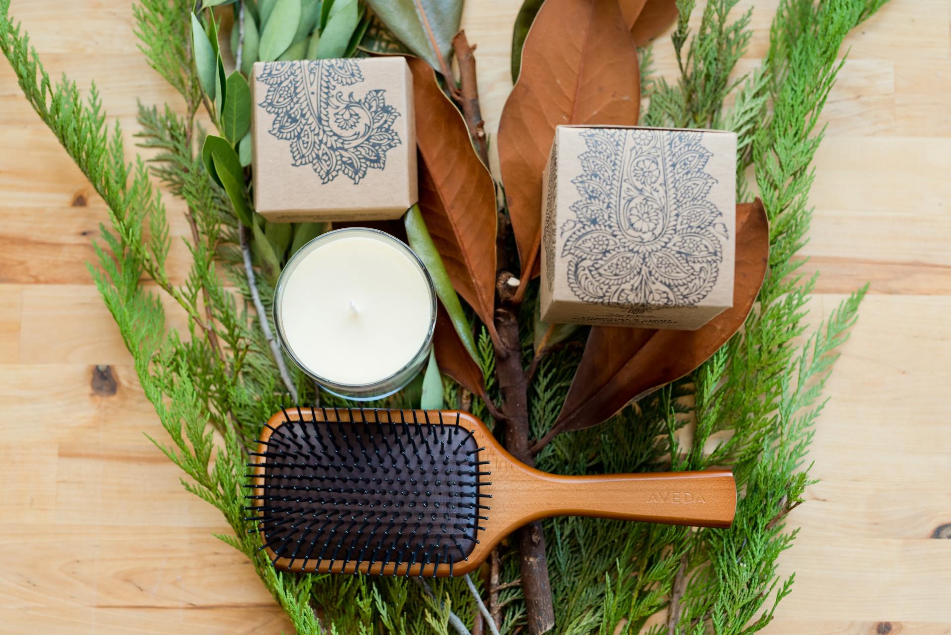 A wooden hairbrush is sitting on top of a wooden table surrounded by plants.
