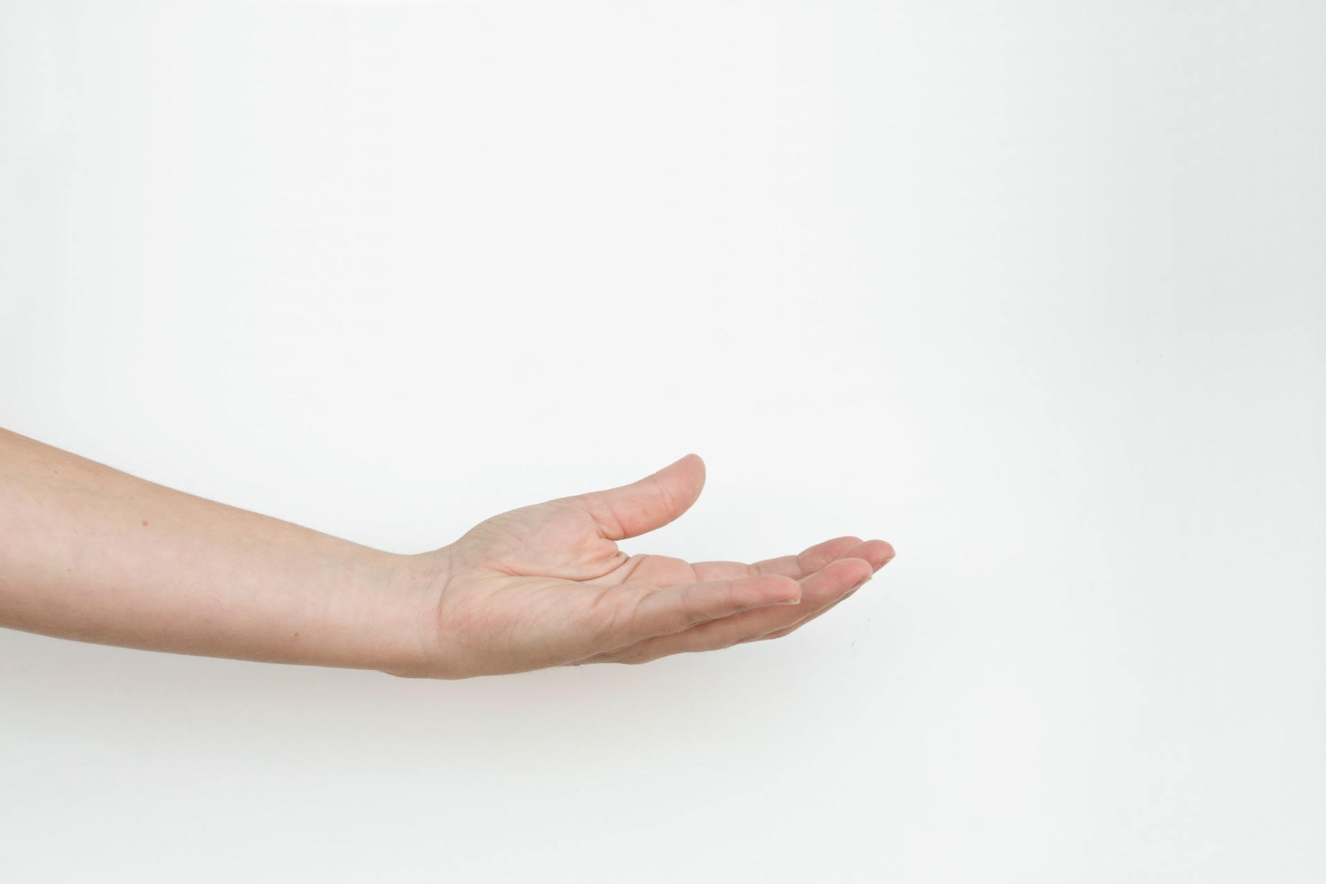 A woman 's hand is reaching out towards the camera on a white background.