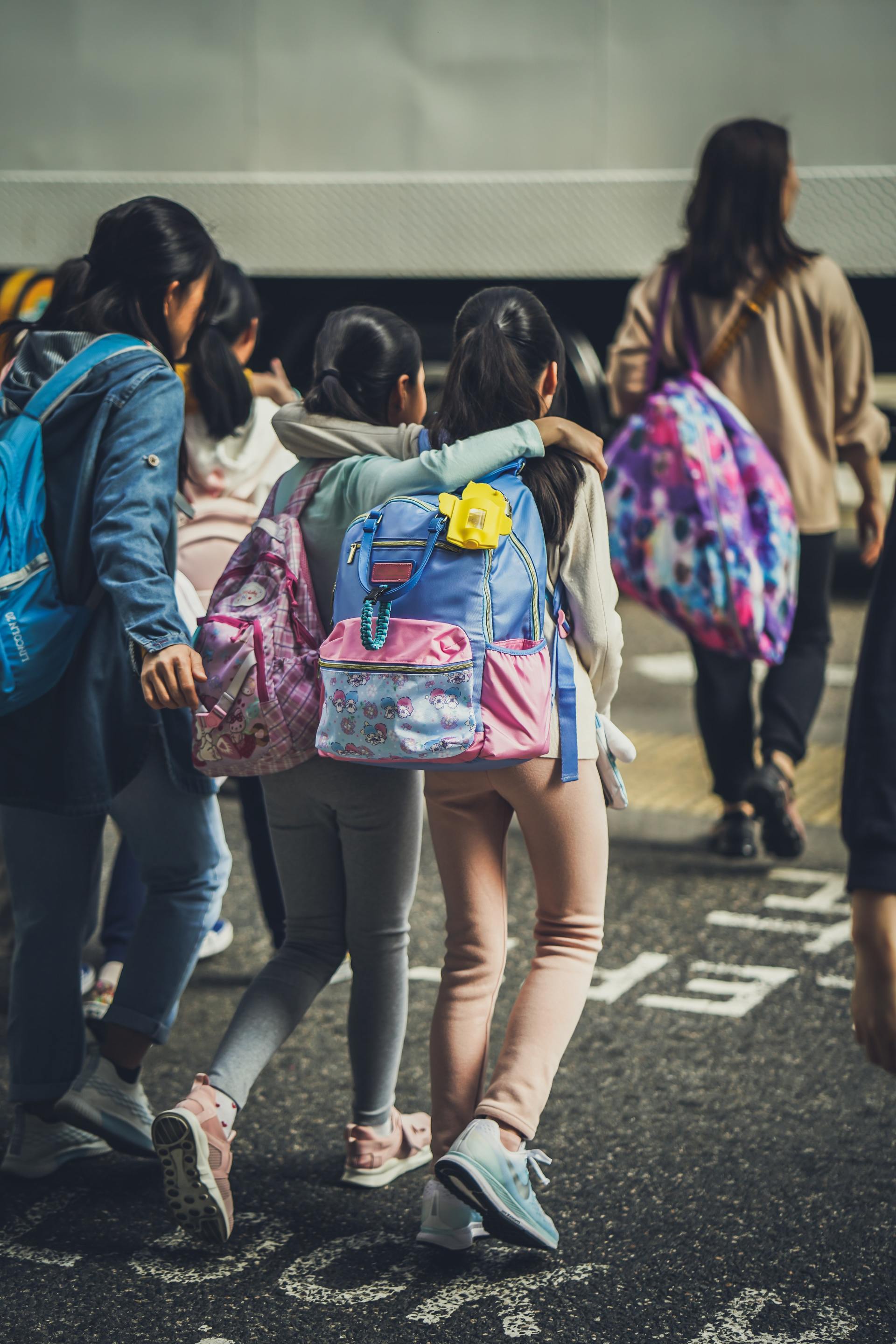 A group of children with backpacks are walking down the street.