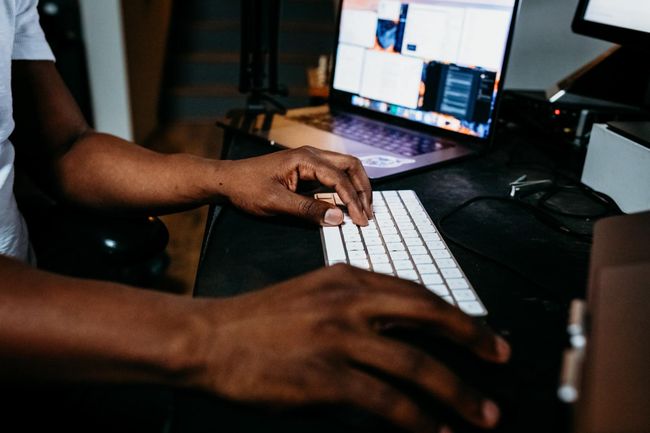 A man is typing on a keyboard in front of a laptop computer.
