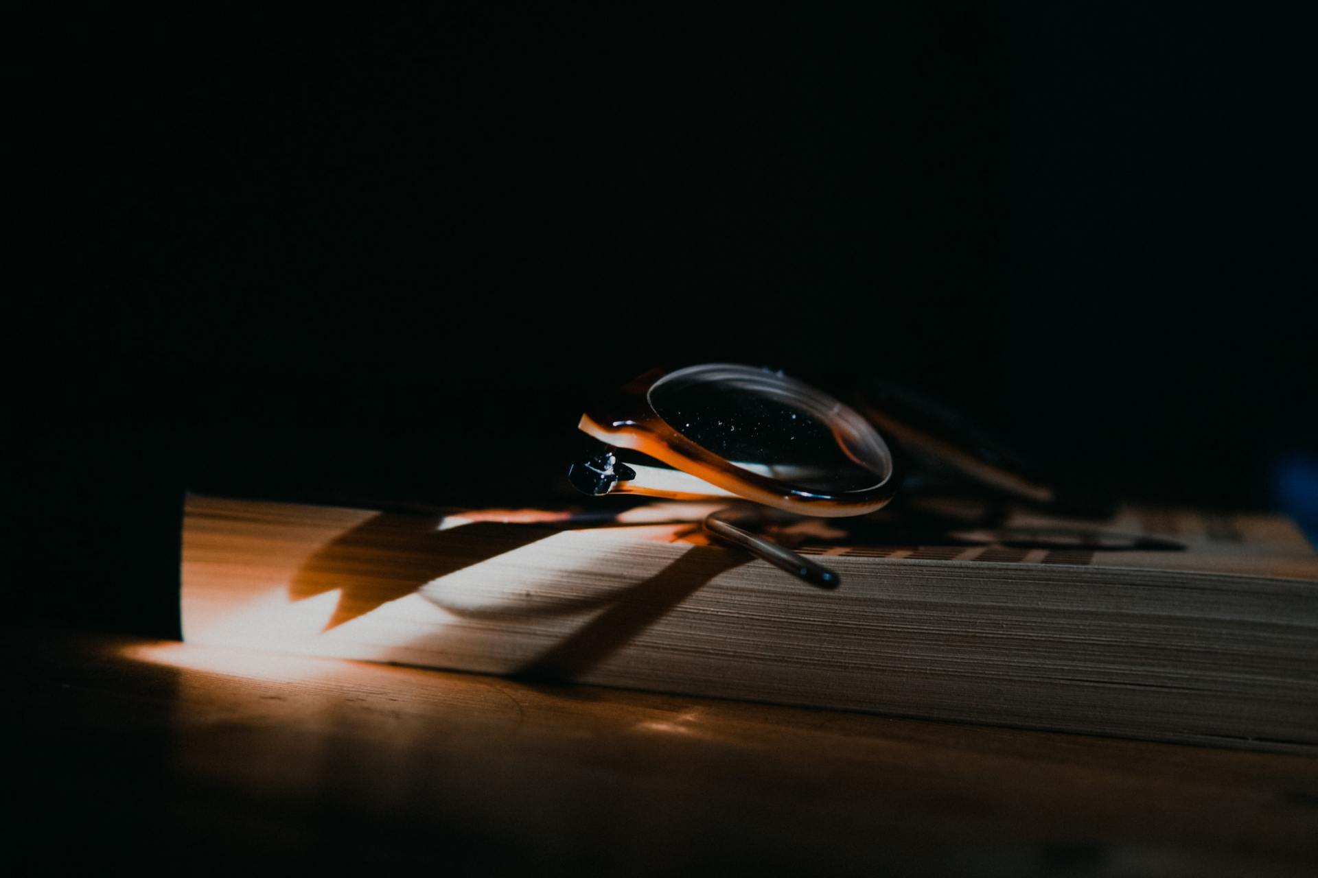 Magnifying glass focusing sunlight to ignite a match on a wooden surface