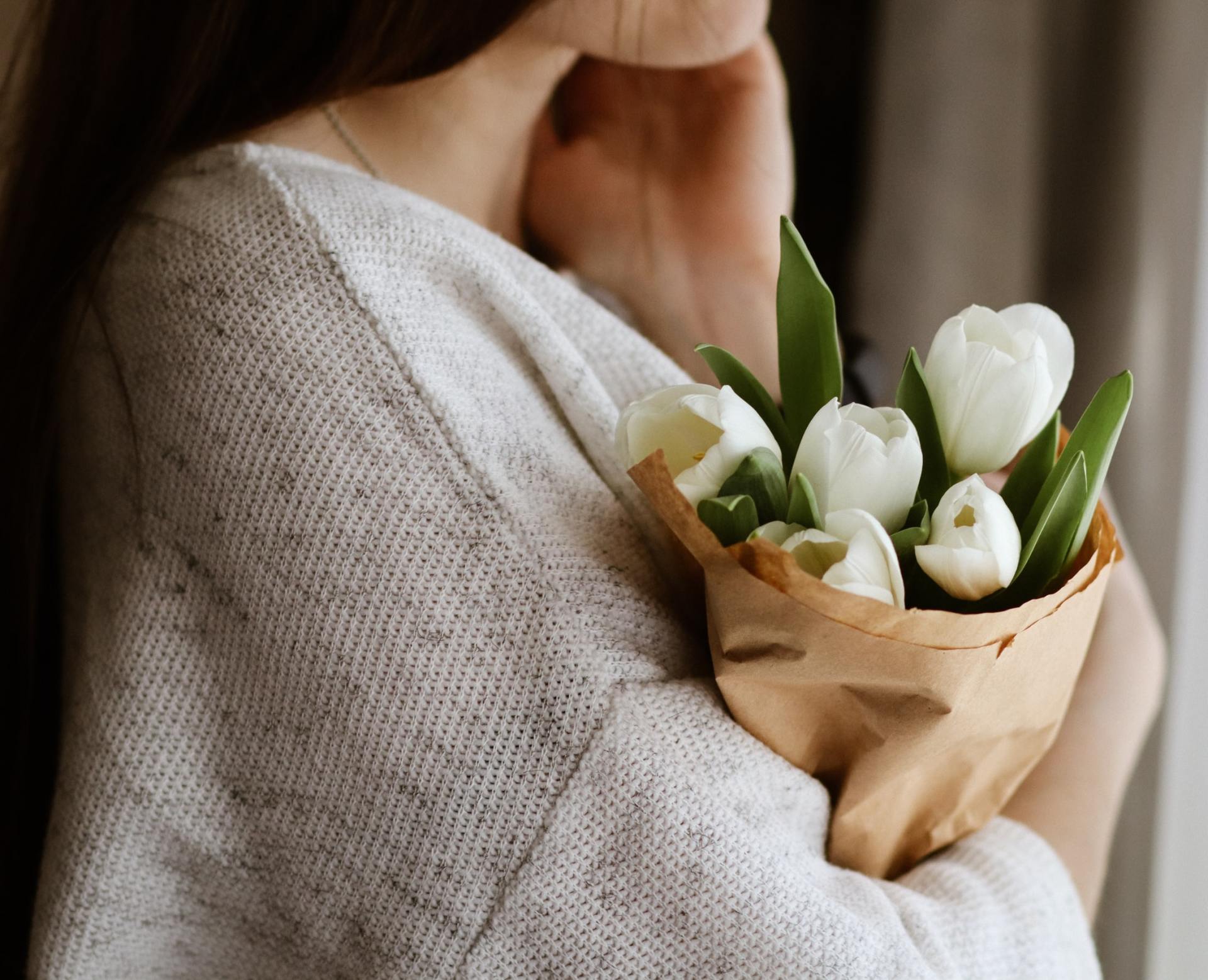 A woman is holding a bouquet of white flowers in her arms.