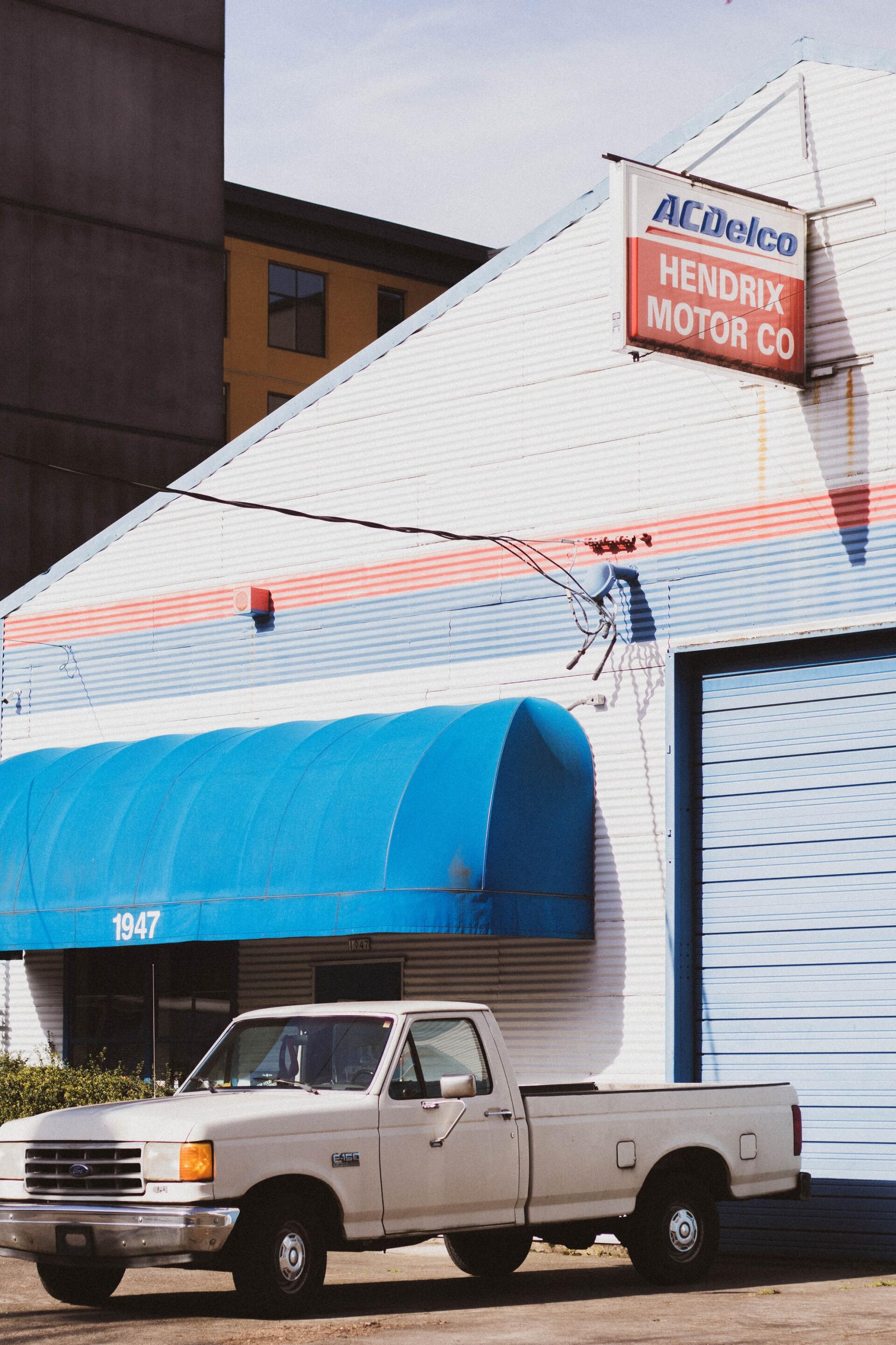 A white truck is parked in front of a building that says acdelco