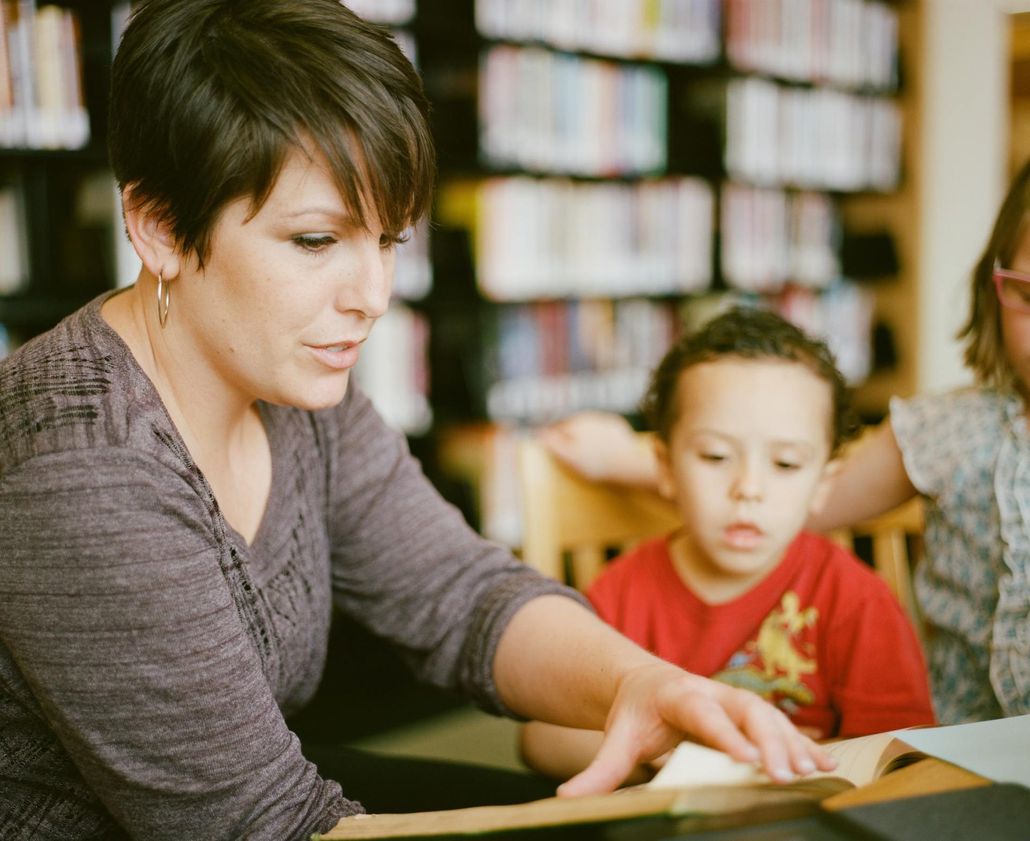 A woman is reading a book to two children in a library