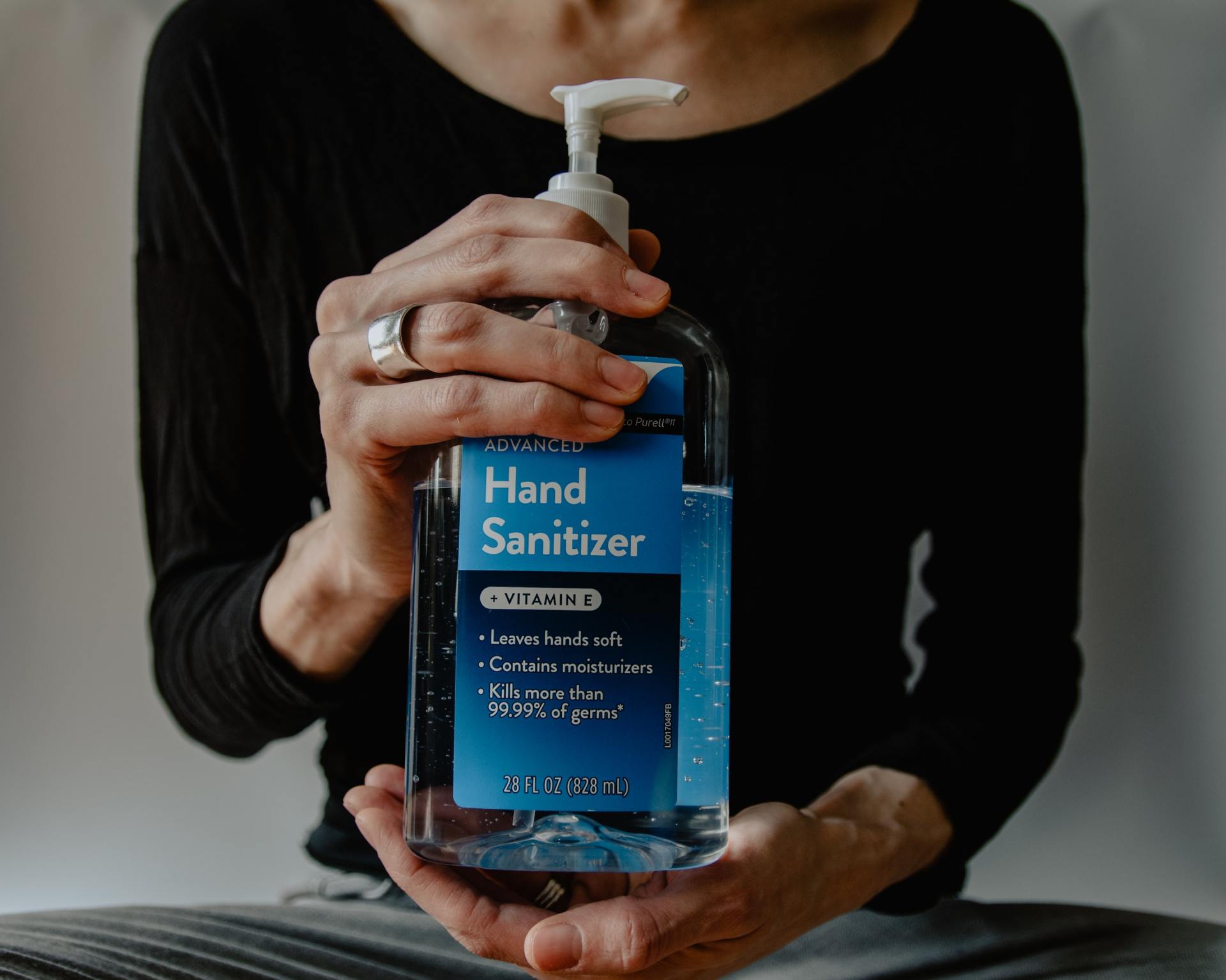 Een vrouw houdt een fles handontsmettingsmiddel in haar handen.