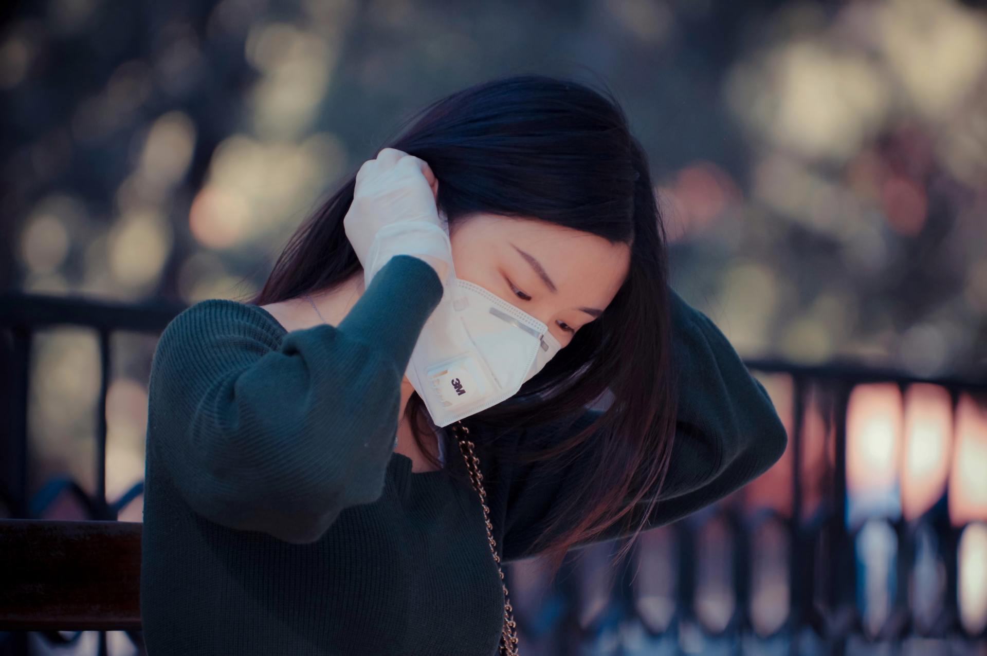 A woman wearing a face mask is sitting on a bench.