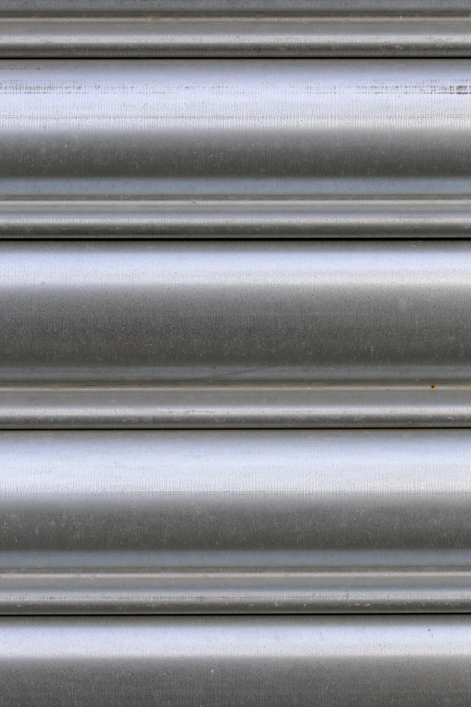 Close-up of a metallic roll-up shutter with horizontal ridges and silver-gray bands