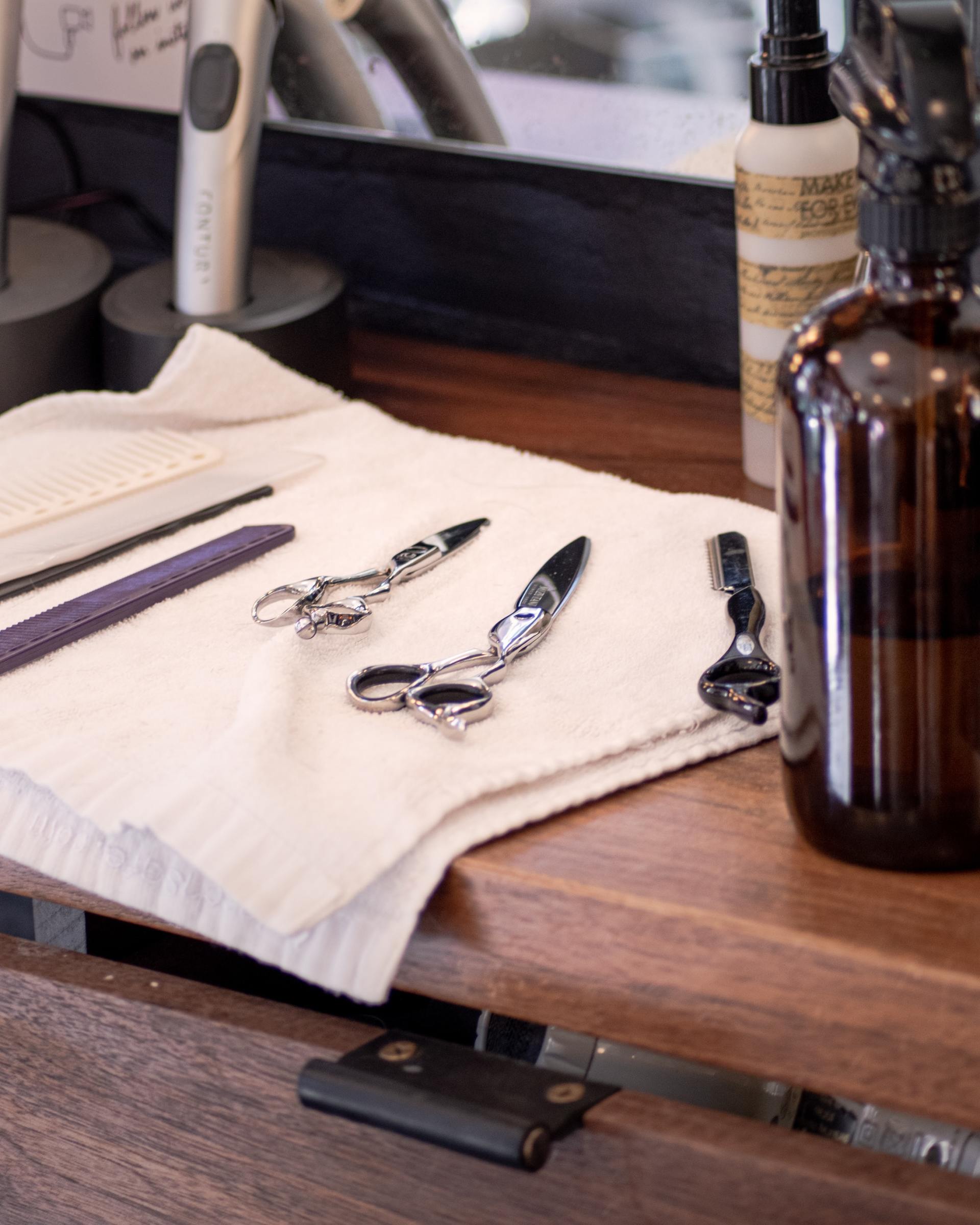 A pair of scissors sit on a towel on a wooden table