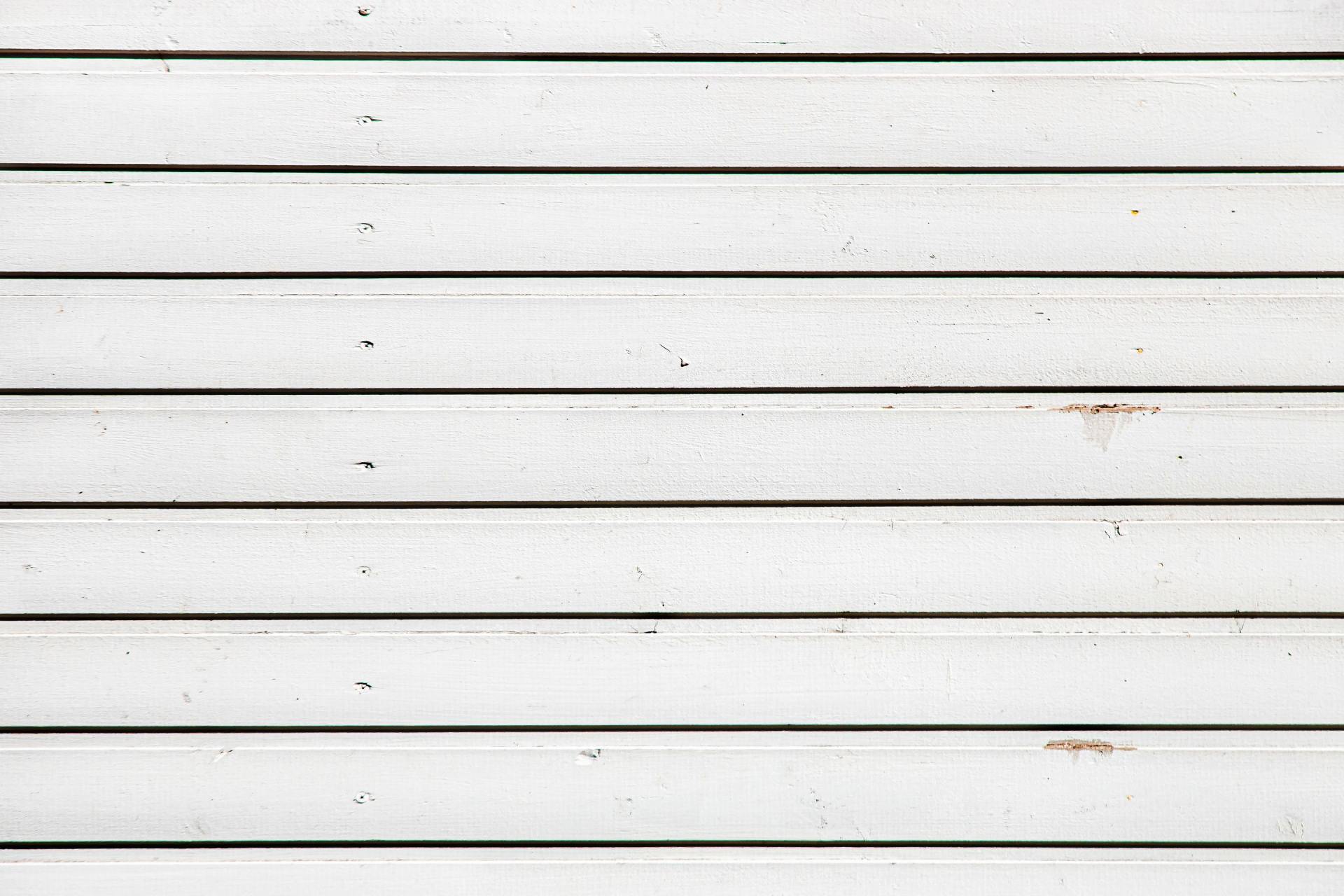 White horizontal wooden planks, close-up with visible texture and black lines between.