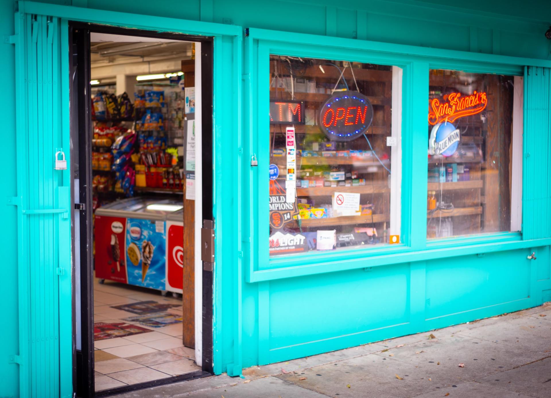 A blue store front with a neon sign that says `` open ''.