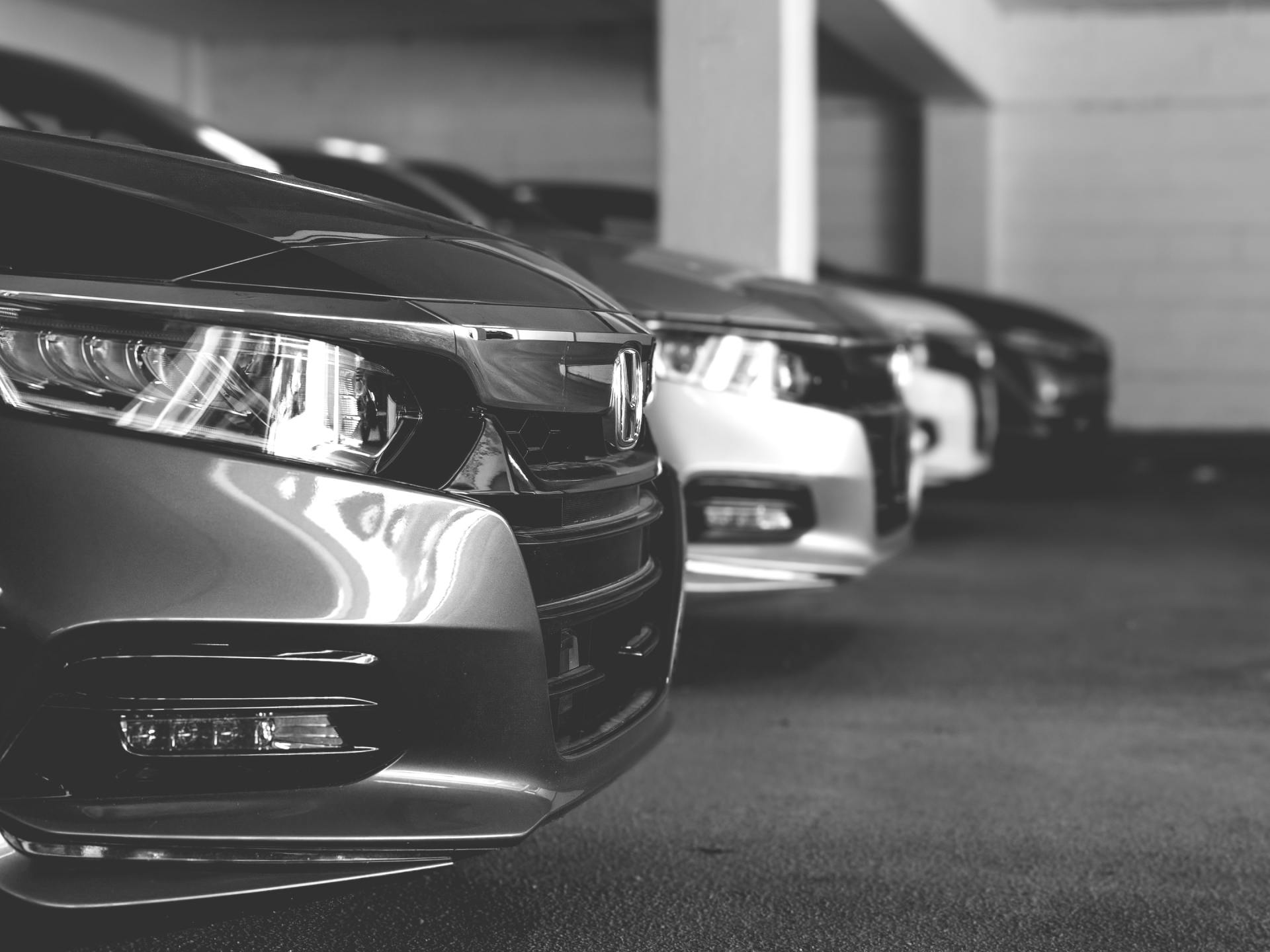Row of parked cars in a garage, with a silver car in the foreground.