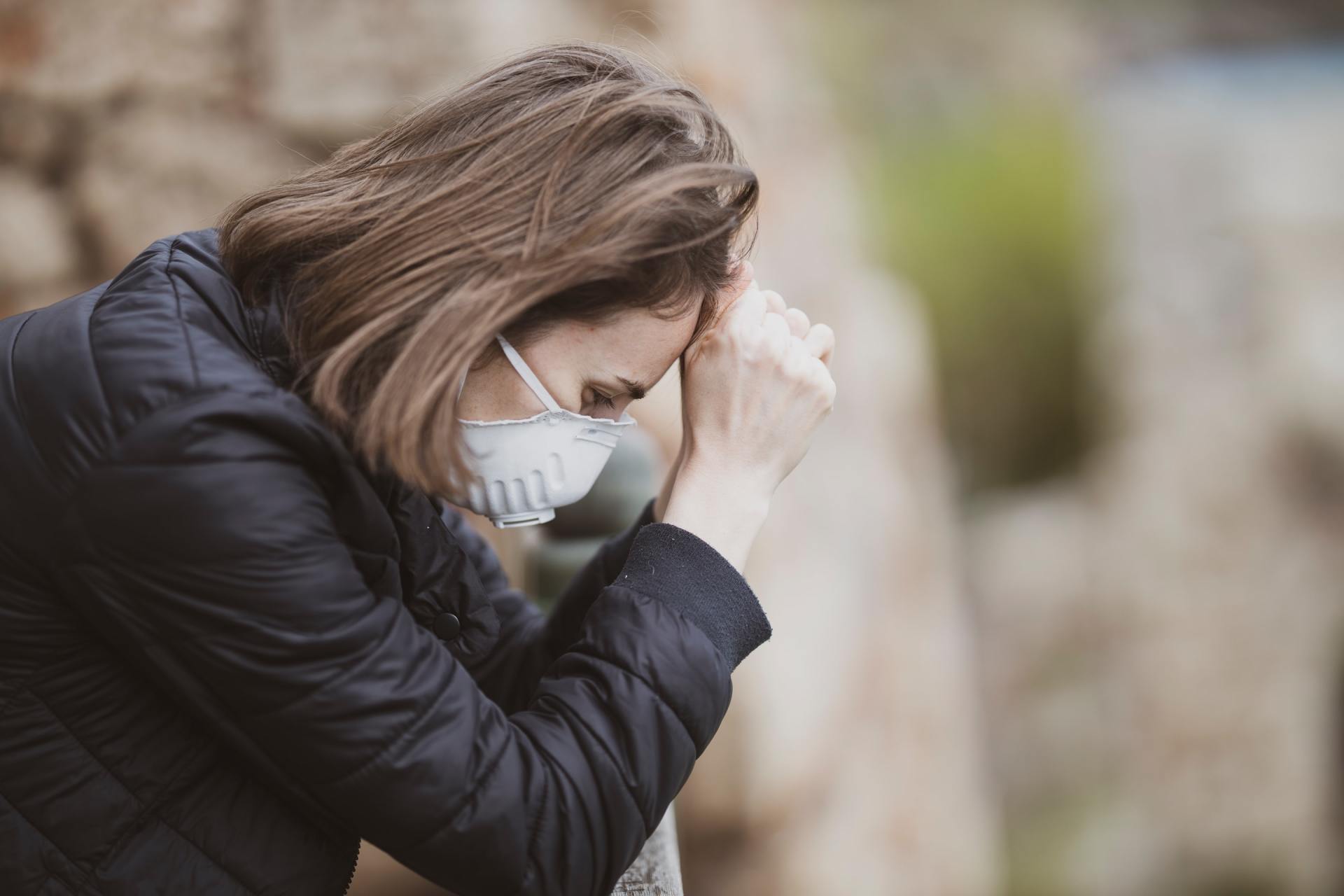 woman looking sad with mask on and head down