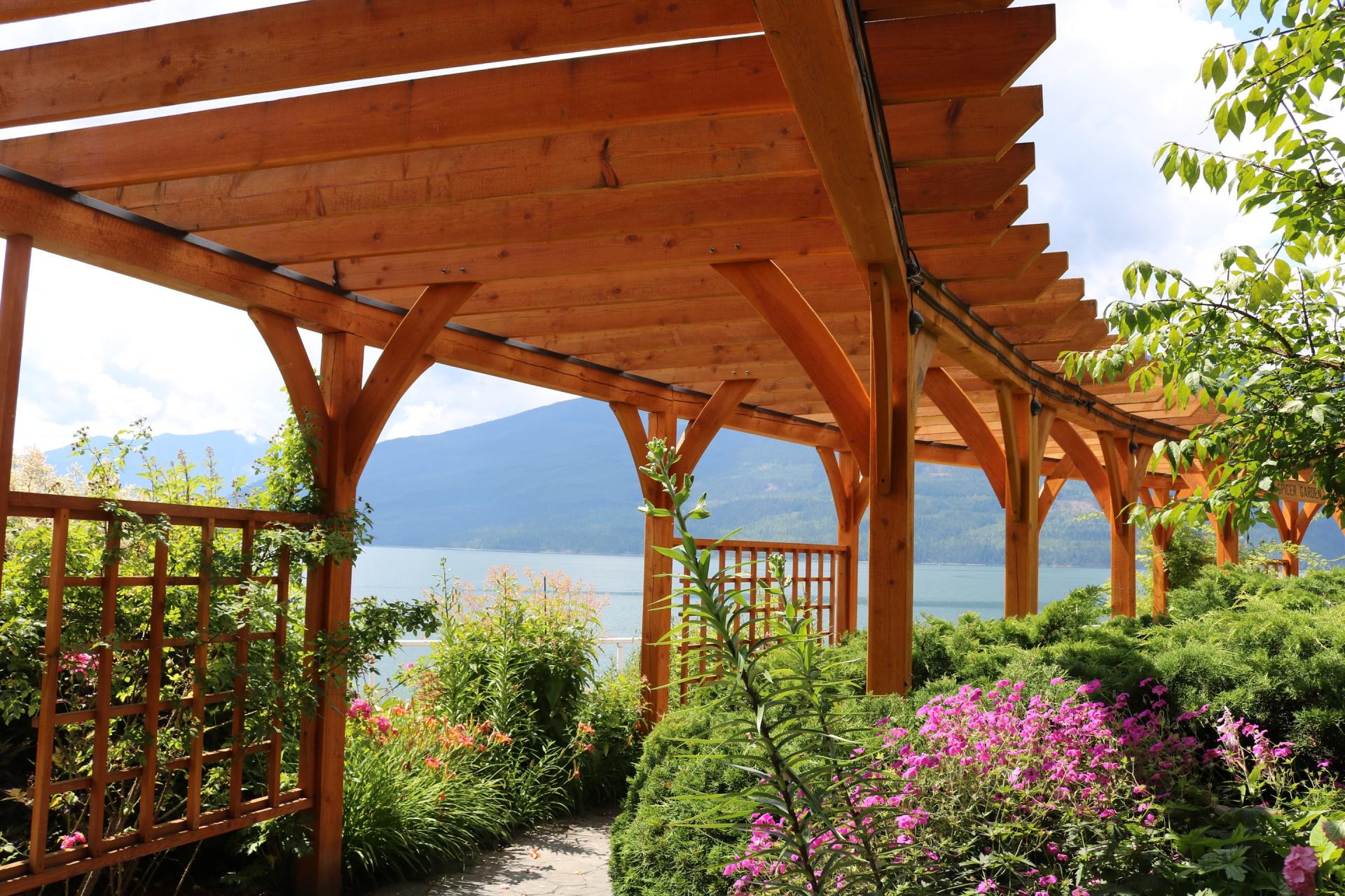 A wooden pergola overlooking a lake with mountains in the background