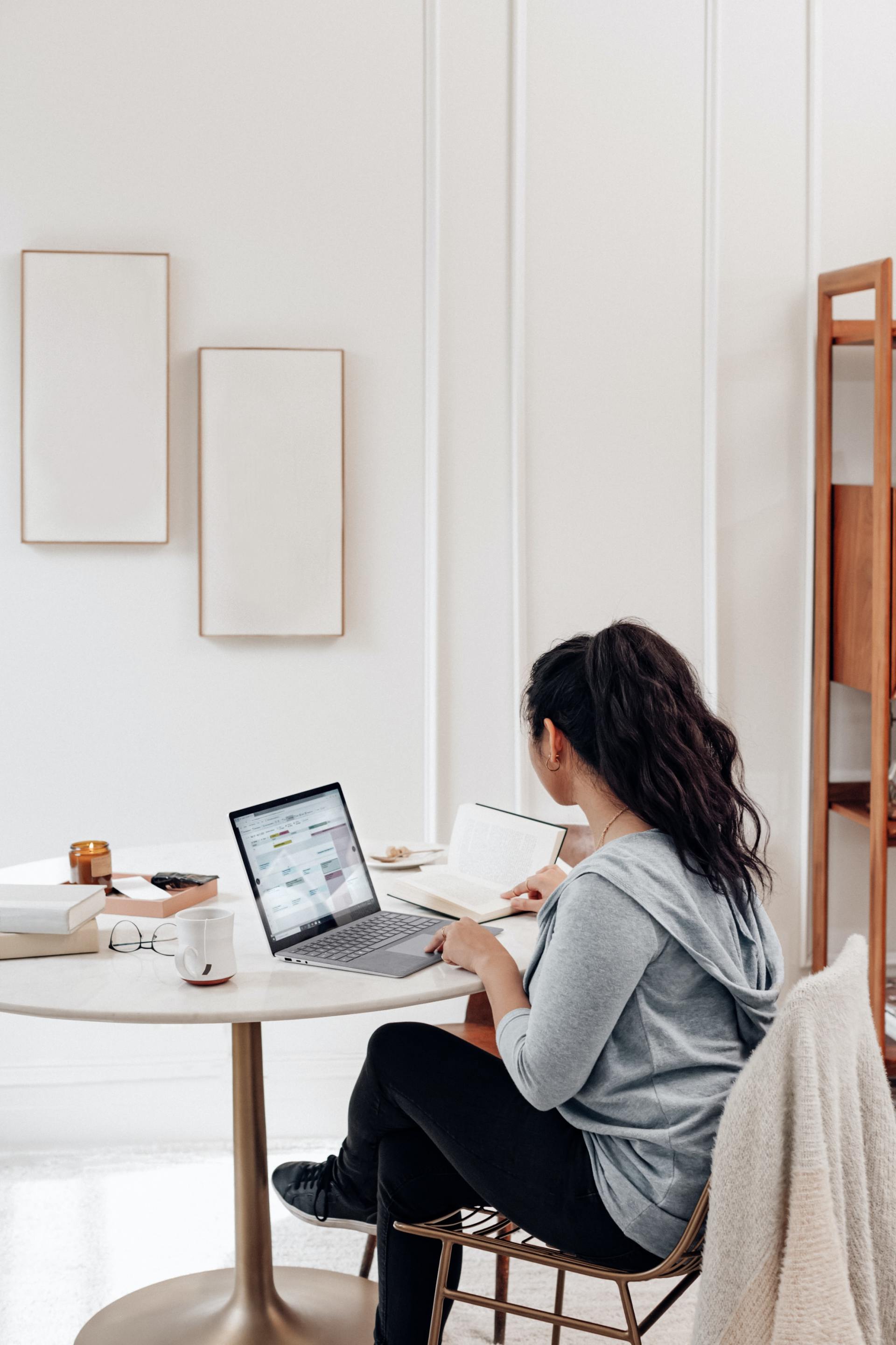 Una mujer está sentada en una mesa utilizando una computadora portátil.