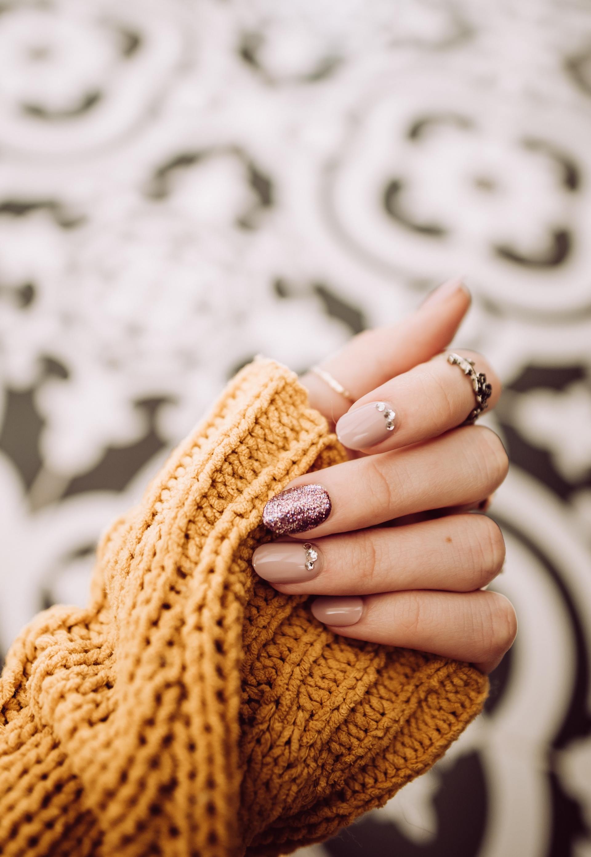 A woman is wearing a yellow sweater and holding her hands together.