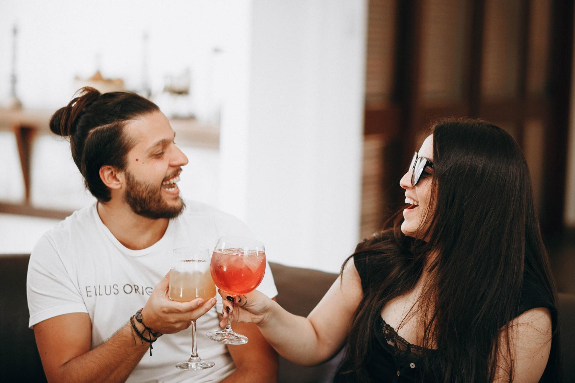 Un uomo e una donna seduti su un divano con in mano dei drink