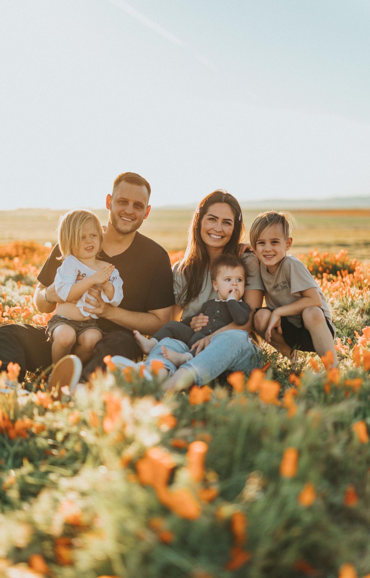 A family is sitting in a field of flowers.