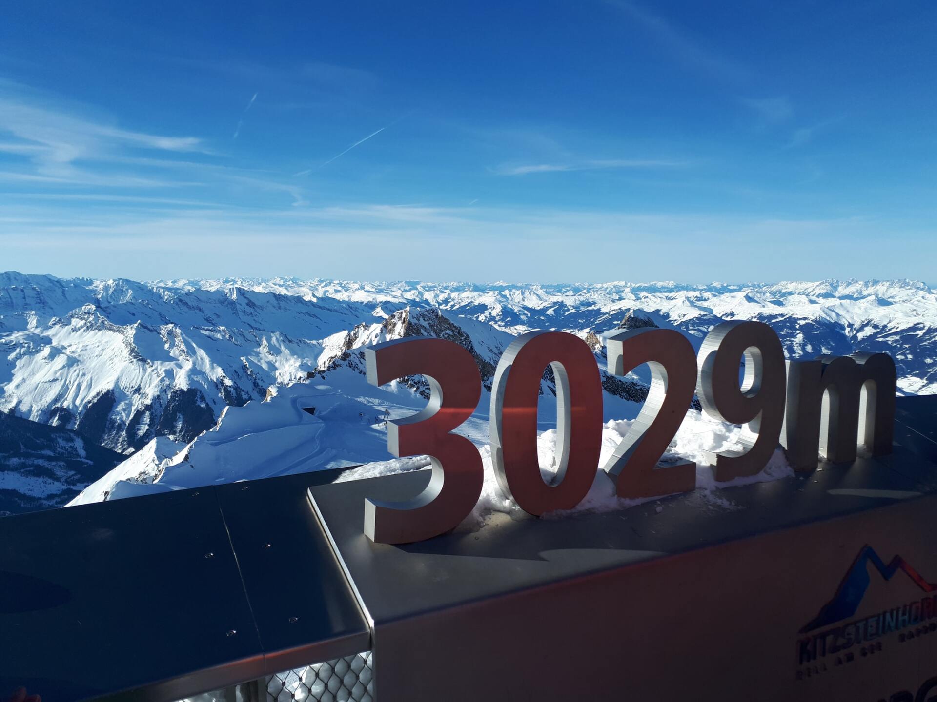 Verschneiter Berggipfel mit der Markierung „3029 m“ unter klarem, blauem Himmel