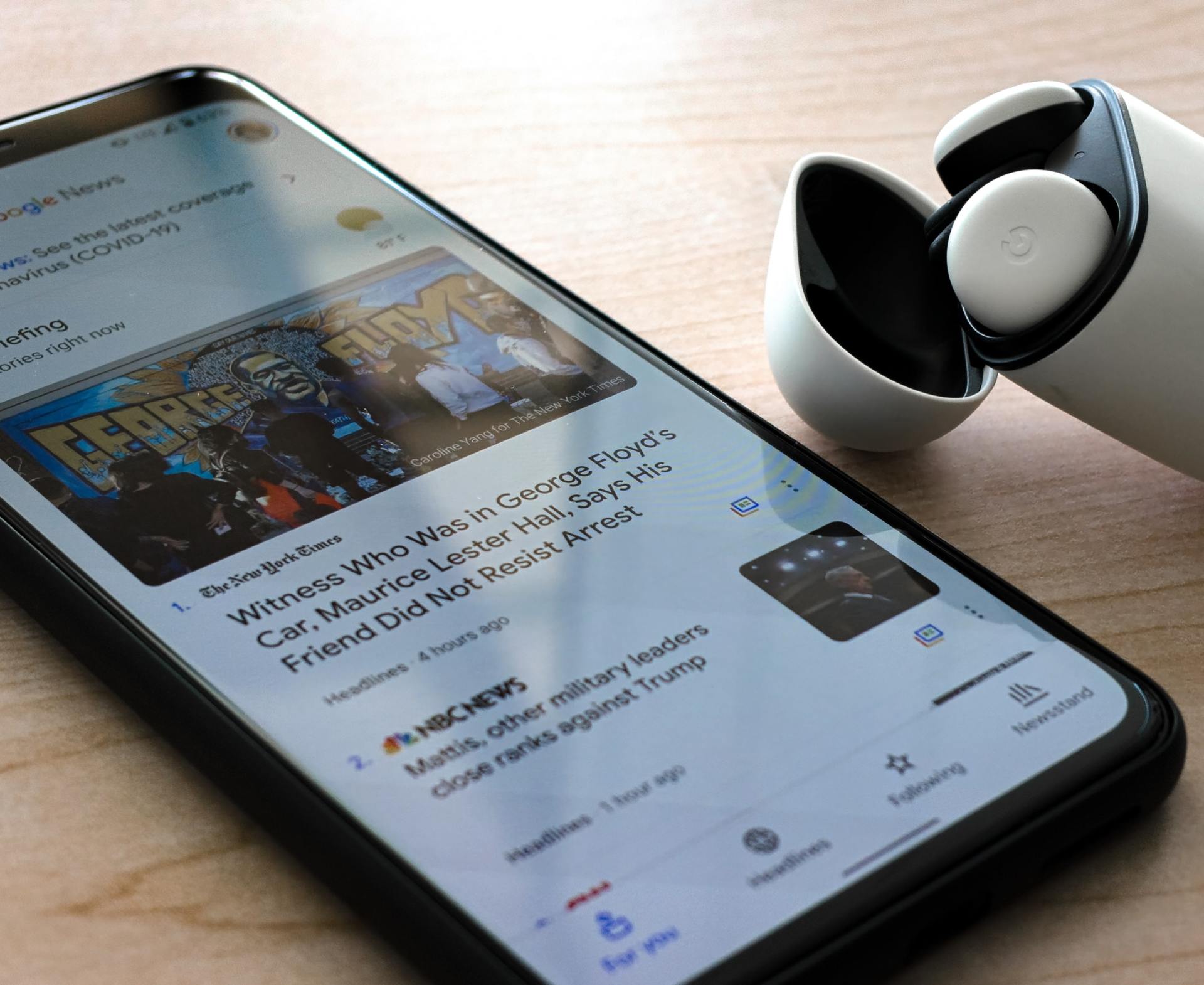 A smart phone with a pair of headphones next to it