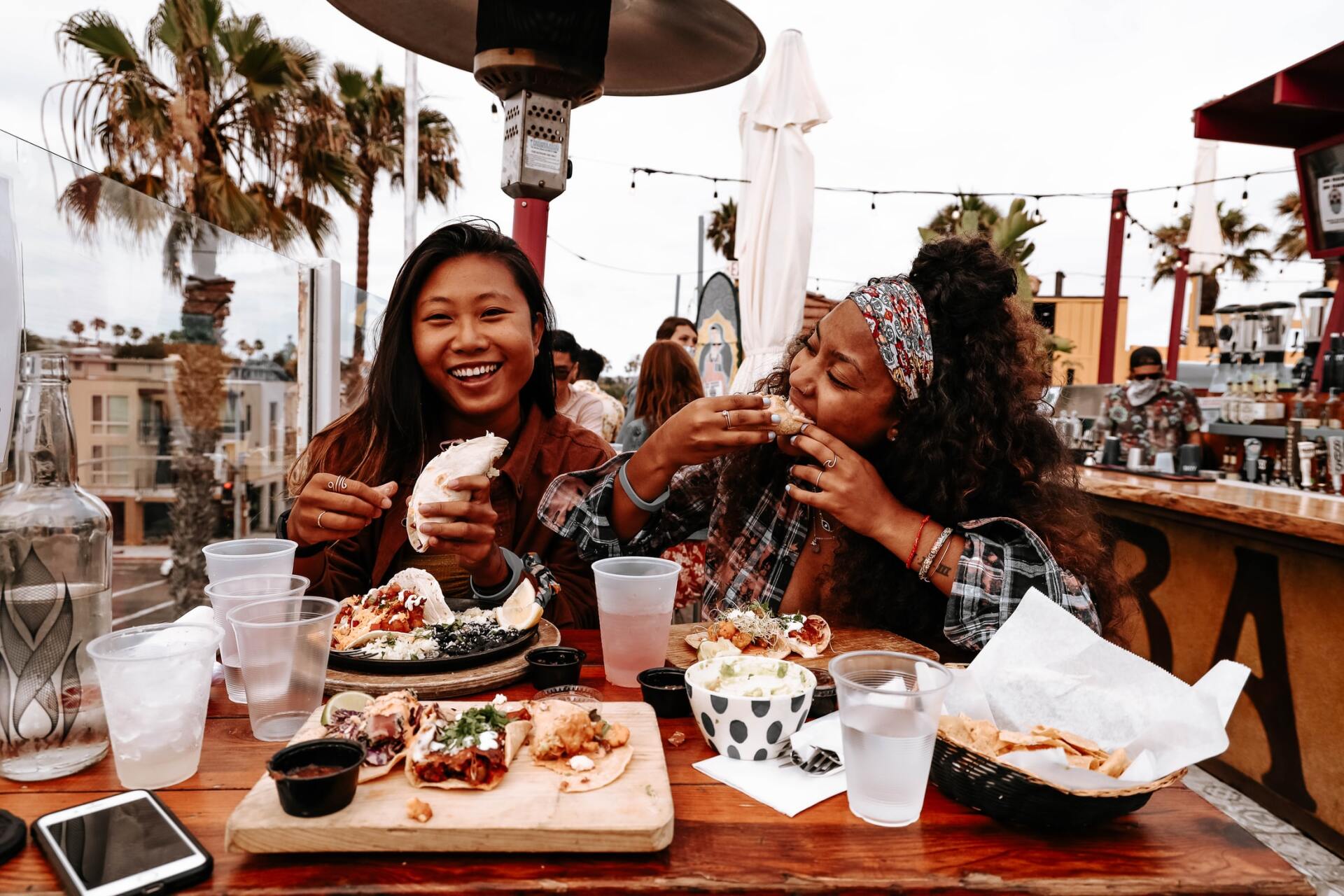 Dos mujeres están sentadas en una mesa comiendo comida.