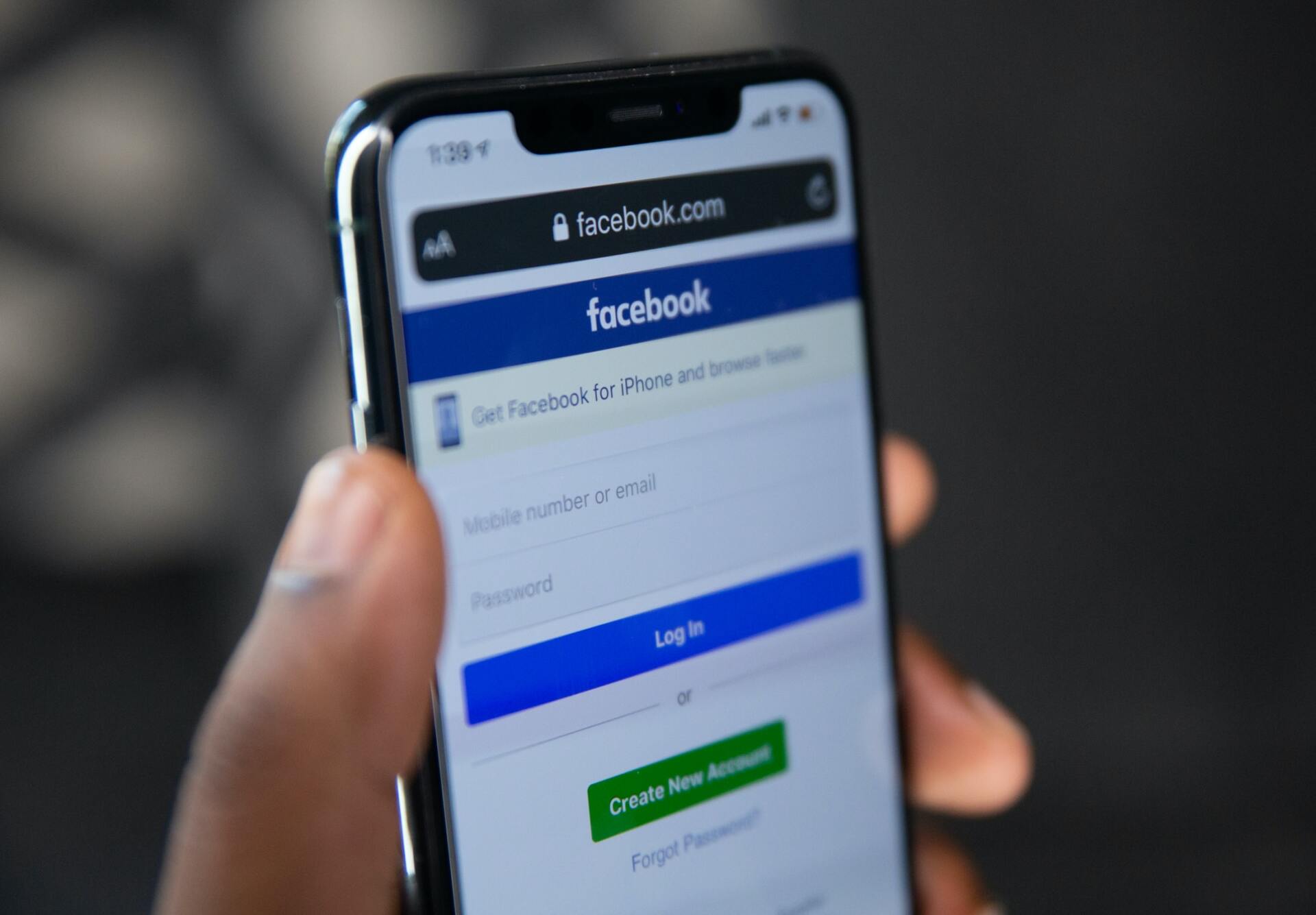 A person is holding a cell phone that is open to a facebook page
